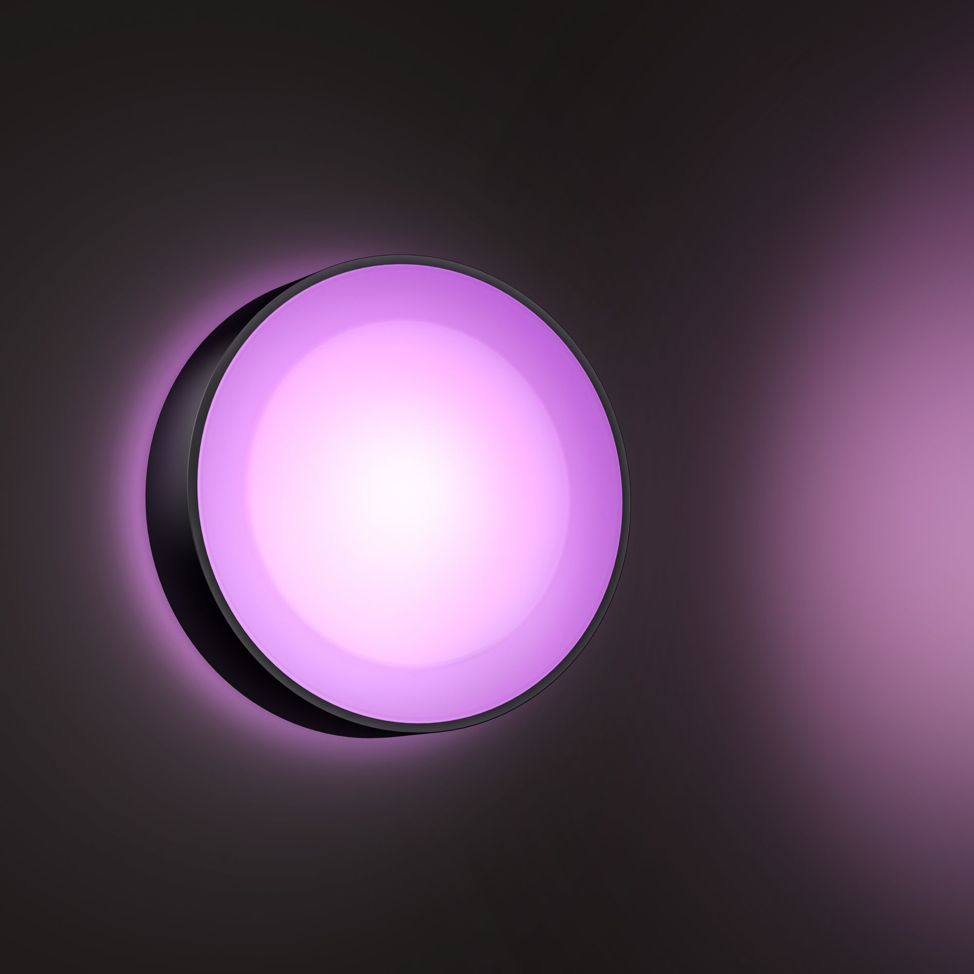 Ronde, zwart omrande wandlamp die roze licht uitstraalt. Het licht staat tegen een grijze achtergrond.
