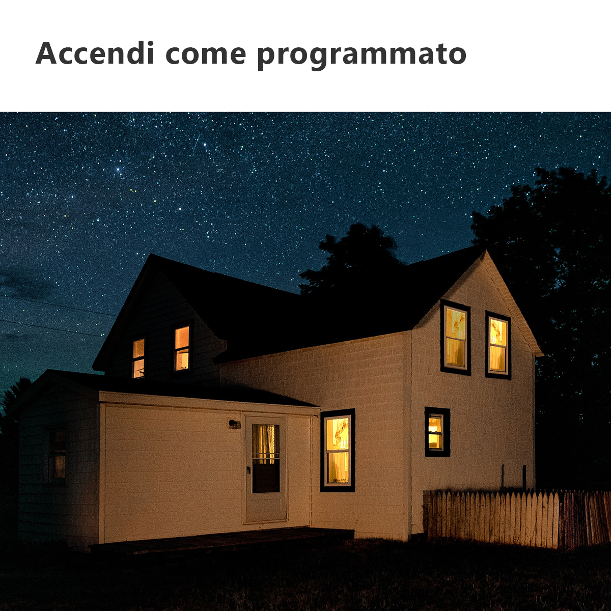 Dom w nocy z podświetlonymi oknami pod gwiaździstym niebem, z płotem na pierwszym planie.