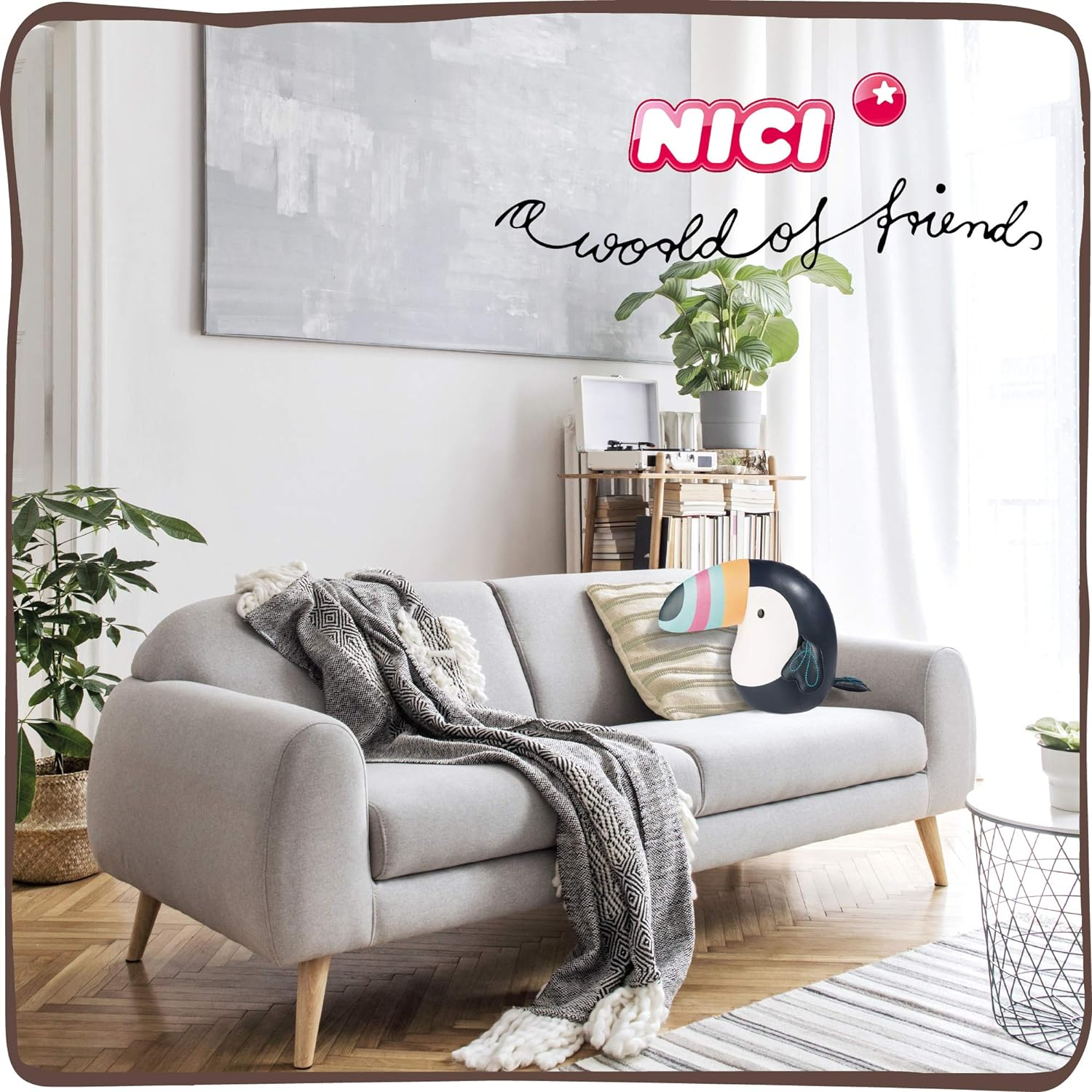 Wohnzimmer mit grauem Sofa, Decke und Tukan-Kissen. Ein Gemälde hängt darüber, und rechts steht eine Pflanze.