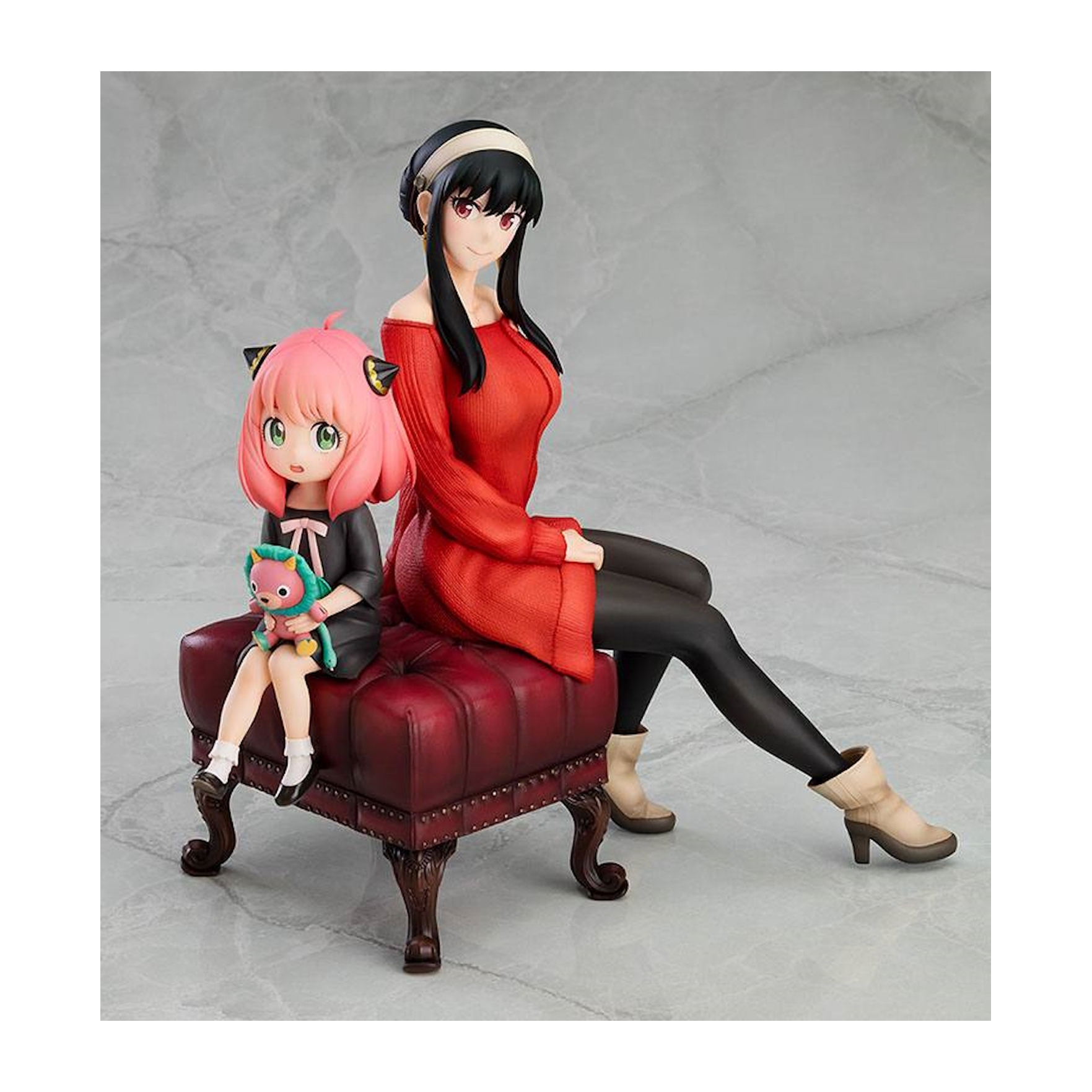 Anime-Figuren einer Frau und eines Kindes. Die Frau ist in Rot, das Kind in Schwarz, auf einem roten Hocker sitzend.