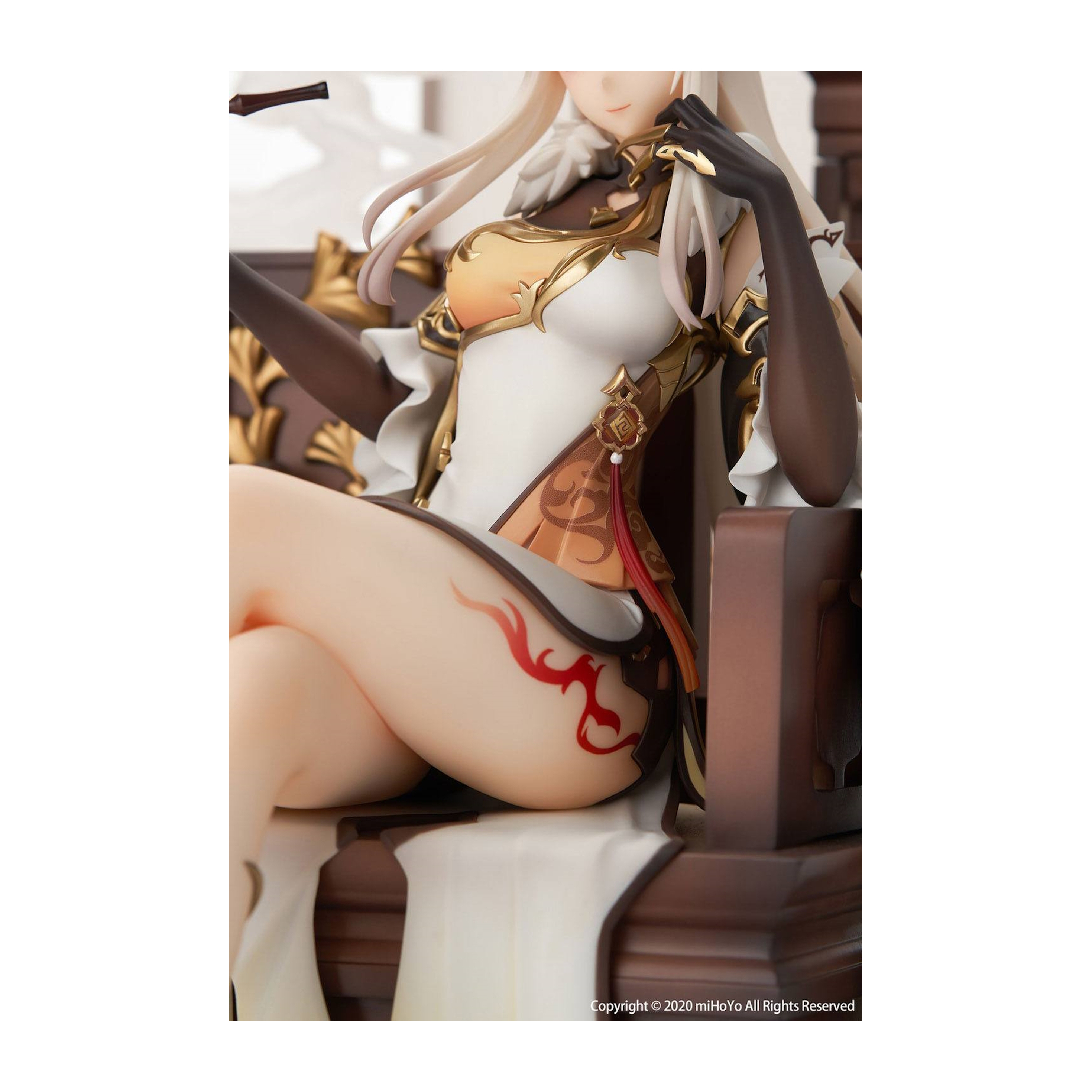 Eine Figur mit weißem Kleid und goldenen Details, die auf einem braunen Stuhl sitzt. Rote Markierungen am Oberschenkel.