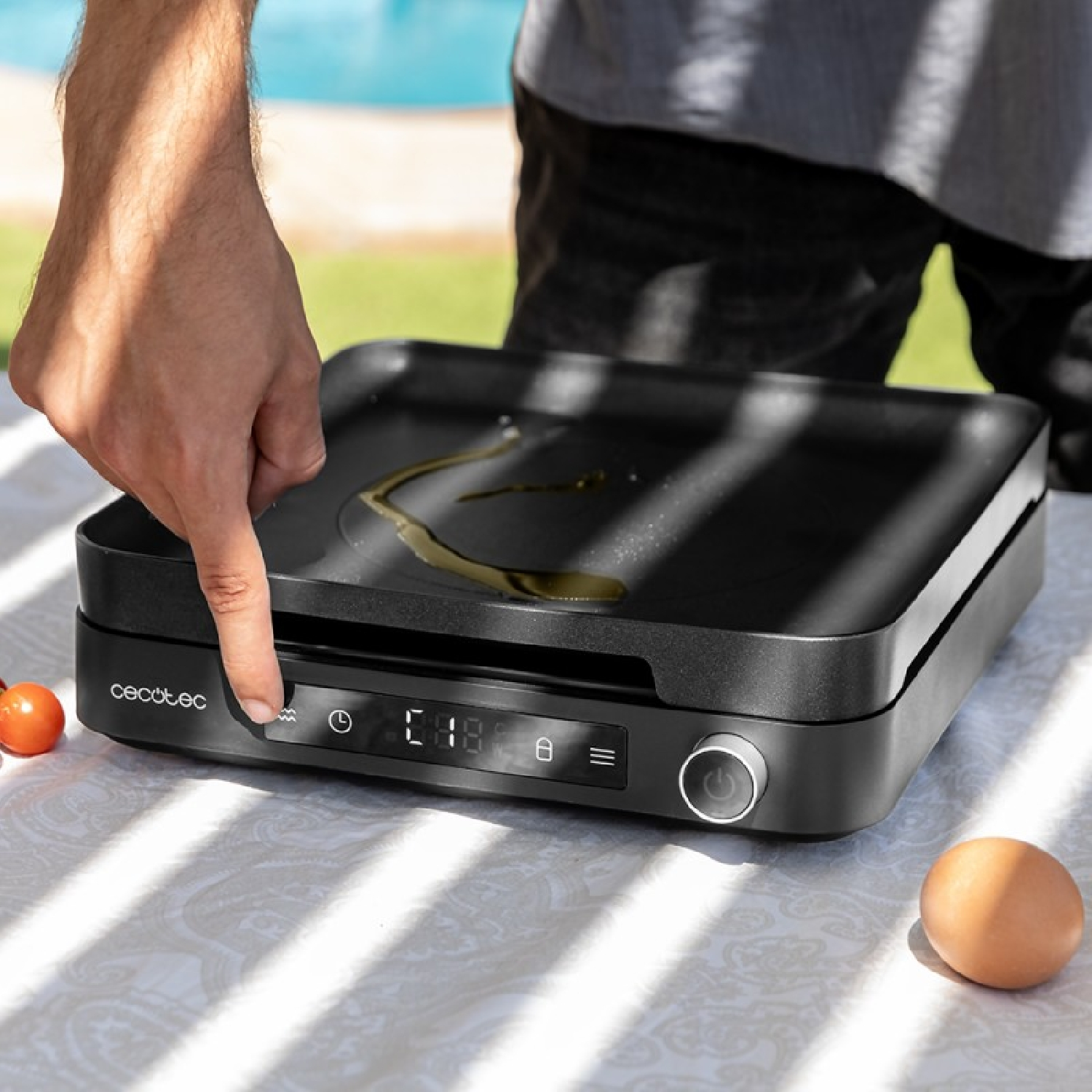 Plancha de cocina en una mesa, la mano de una persona presiona un botón.