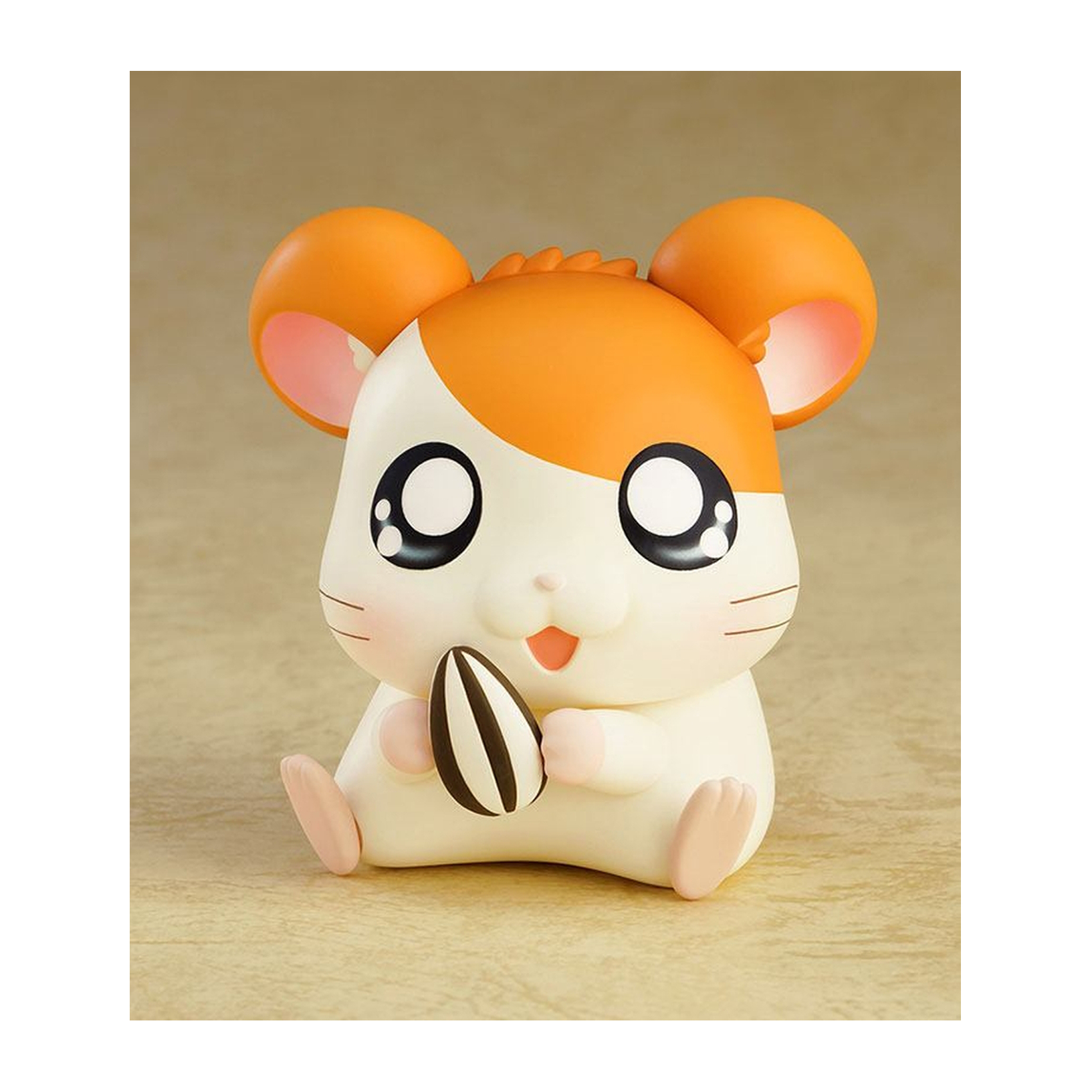 Hamsterspielzeug mit orange-weißem Fell, hält einen Sonnenblumenkern.