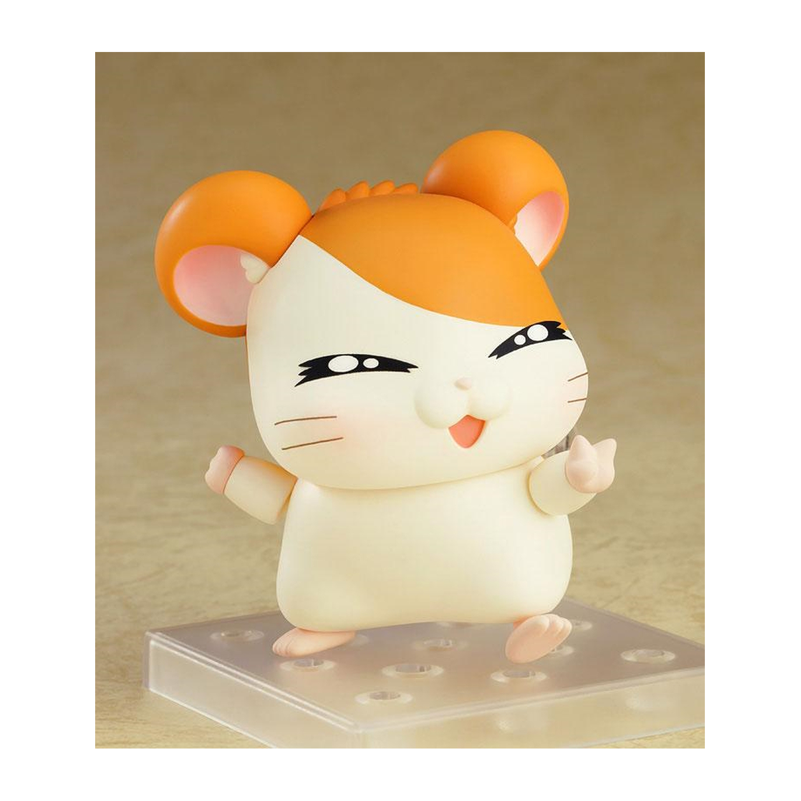 Eine Hamsterfigur mit orangenen Ohren und Wangen. Es lächelt und winkt. Es steht auf einem klaren Sockel.