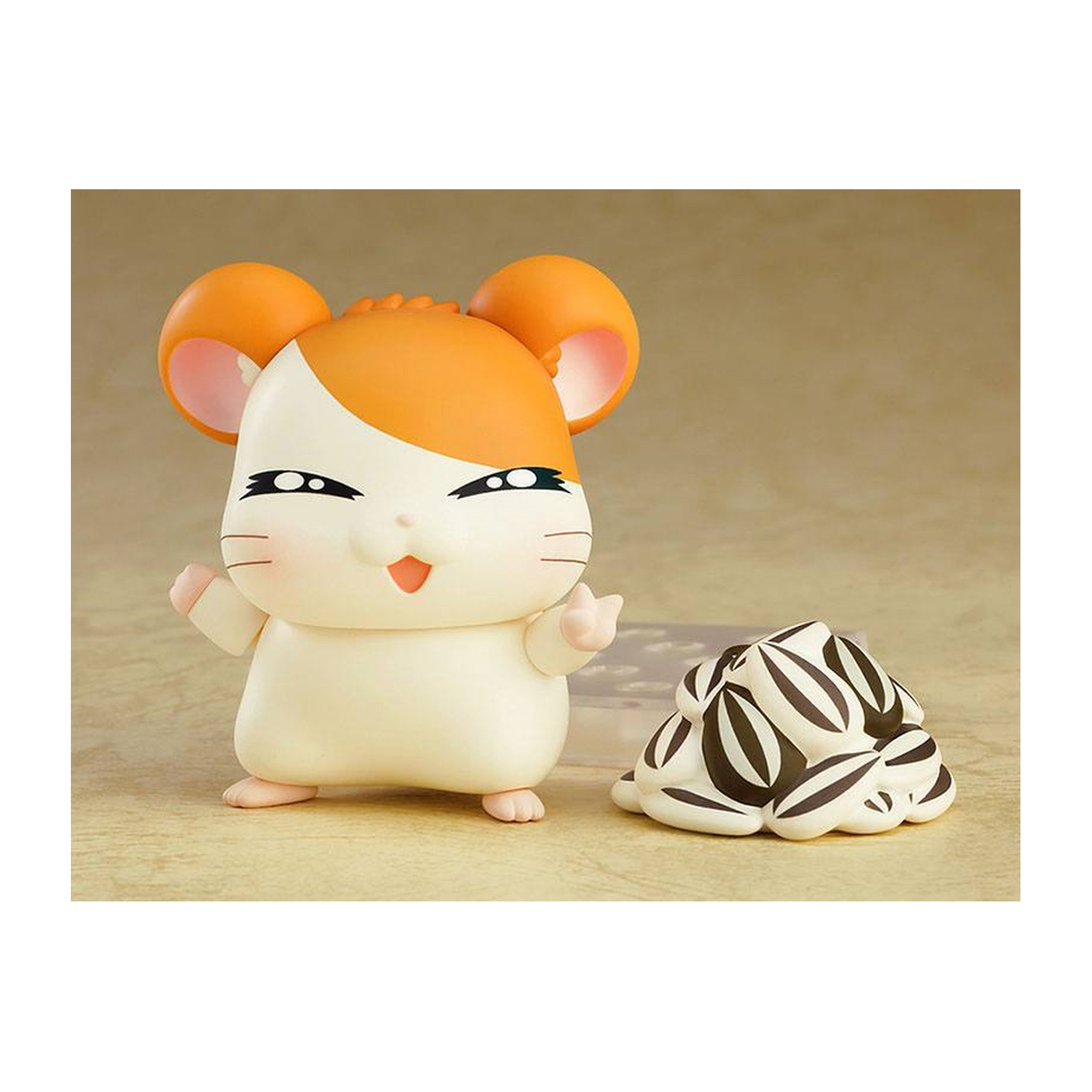 Hamsterfigur mit orange-weißem Fell. Ein kleines Objekt mit weißem und schwarzem Muster ist daneben.