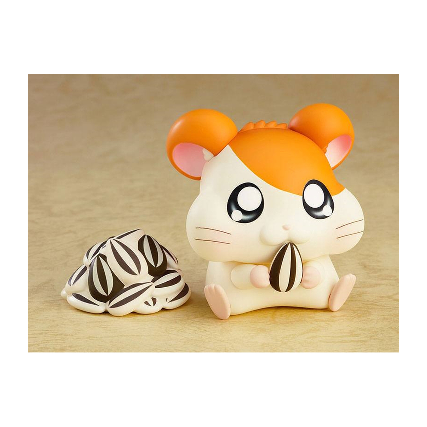Hamsterfigur mit orange-weißem Fell. Hält einen Sonnenblumenkern. Ein Heubett liegt daneben.