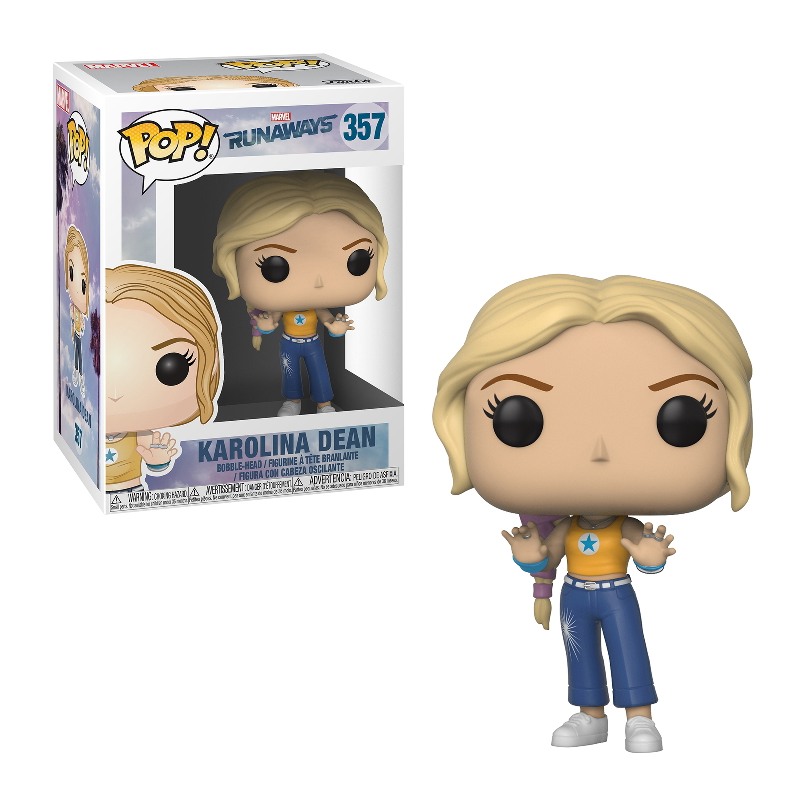 Figura di Karolina Dean con capelli biondi, con top giallo e jeans blu. Scatola sullo sfondo.