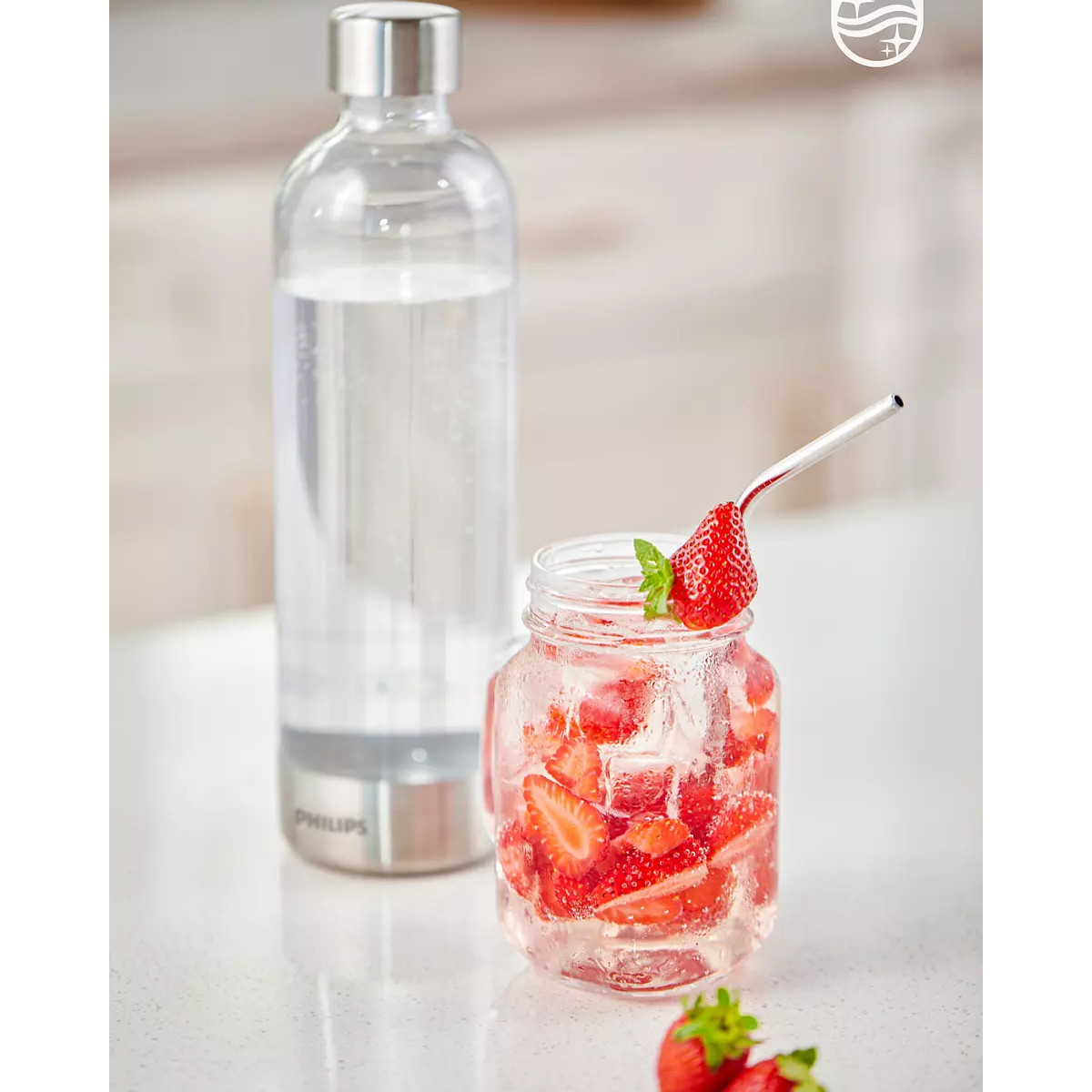 Eine Glasflasche und ein Glas mit Wasser und Erdbeeren. Ein Metallstrohhalm im Glas.