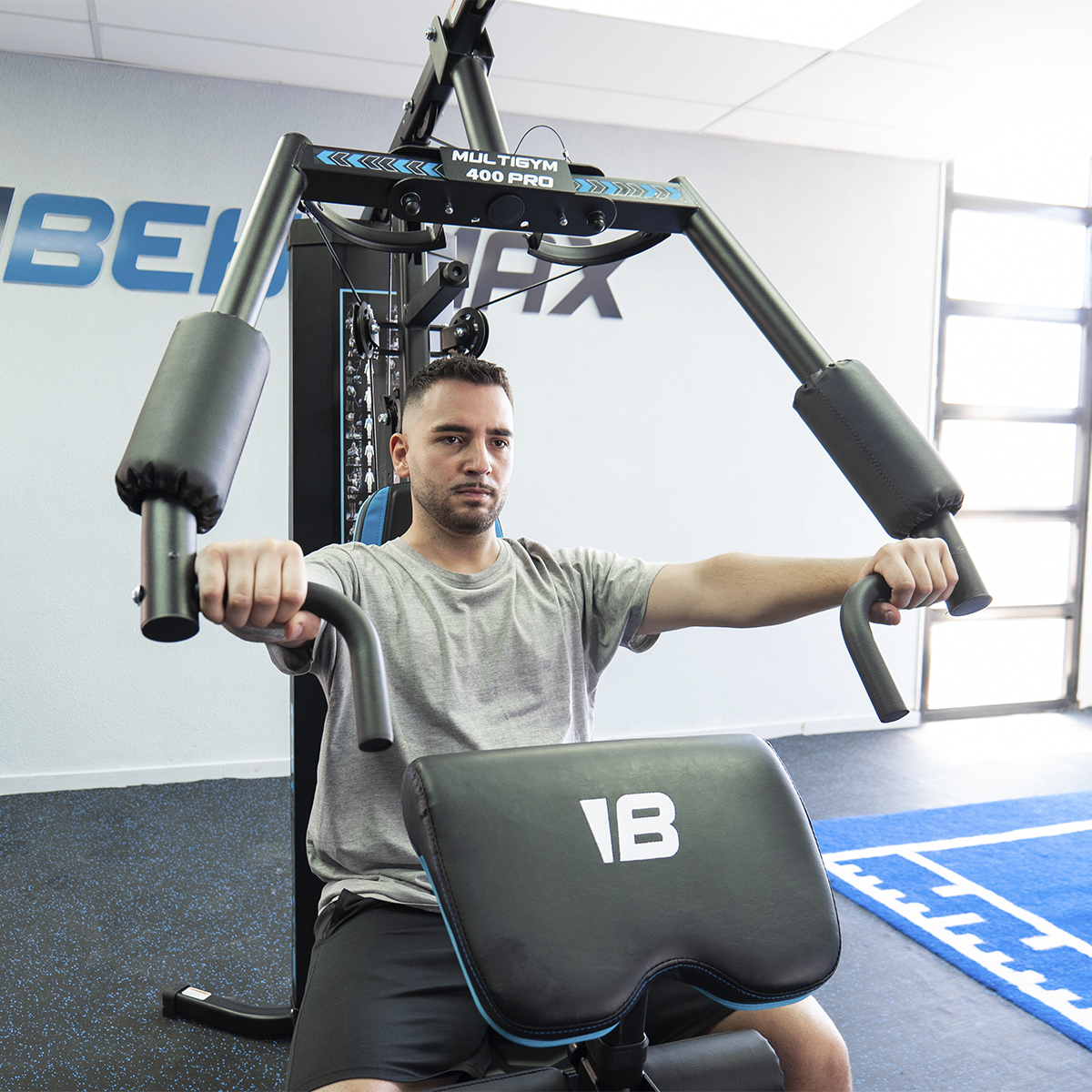 Un hombre haciendo ejercicio en una máquina multi-gimnasio negra y azul en un gimnasio.