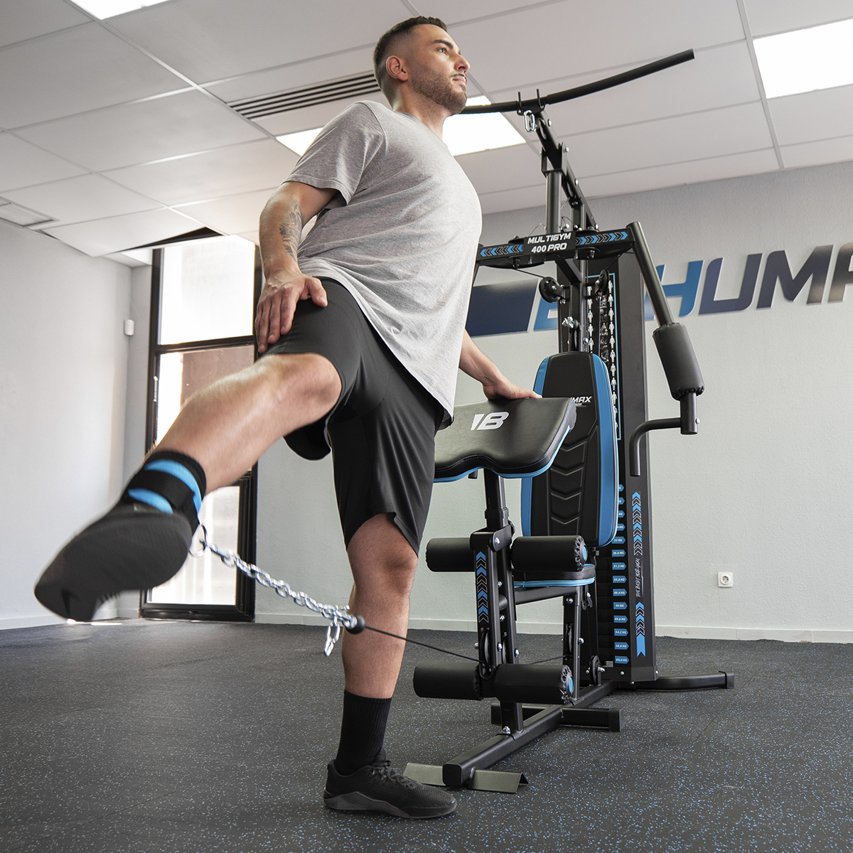 Hombre ejercitándose en una máquina multi-gimnasio, levantando la pierna con un cable.
