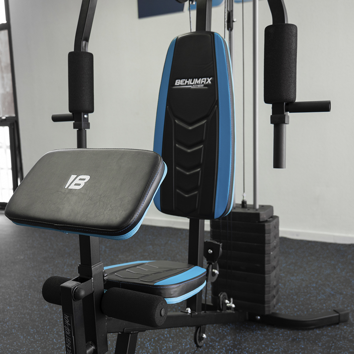 Equipo de gimnasio con detalles en negro y azul. Incluye asiento, respaldo, pesas y soportes para brazos.