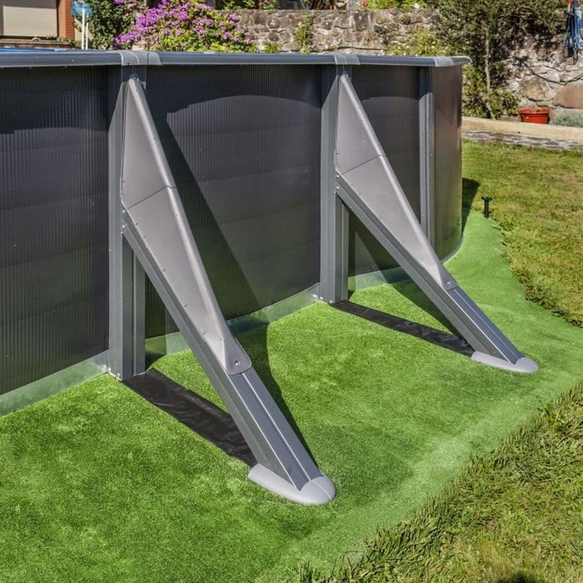 Una sección de piscina con soportes metálicos grises. Césped artificial verde. Contexto: patio trasero.