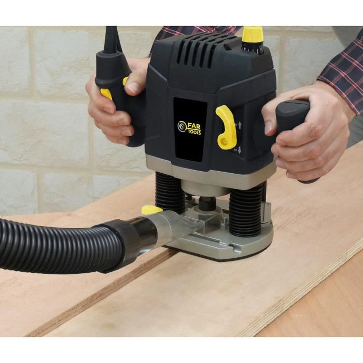 Hände, die ein schwarz-gelbes Elektrowerkzeug auf einer Holzplatte verwenden. Ein flexibler Schlauch ist angebracht.