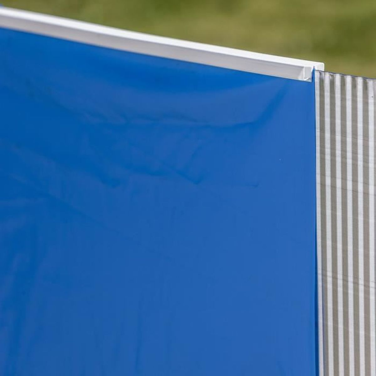 Blaue Kunststoffplatte neben einer vertikal gestreiften grauen Oberfläche mit weißem Rand.