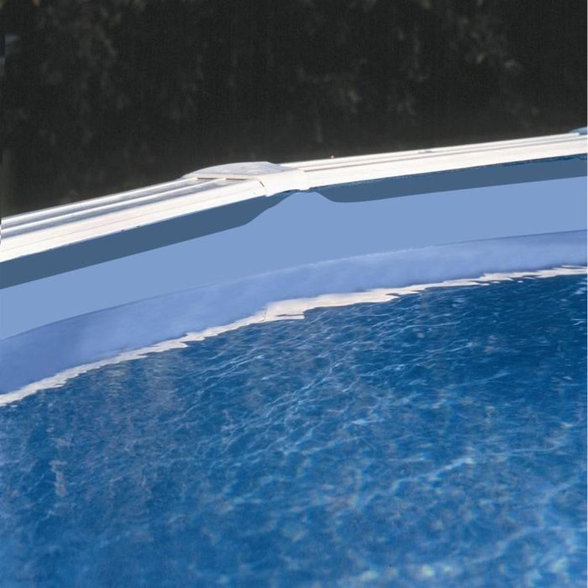 Agua azul en una piscina, con borde blanco y fondo oscuro, superficie ondulada.