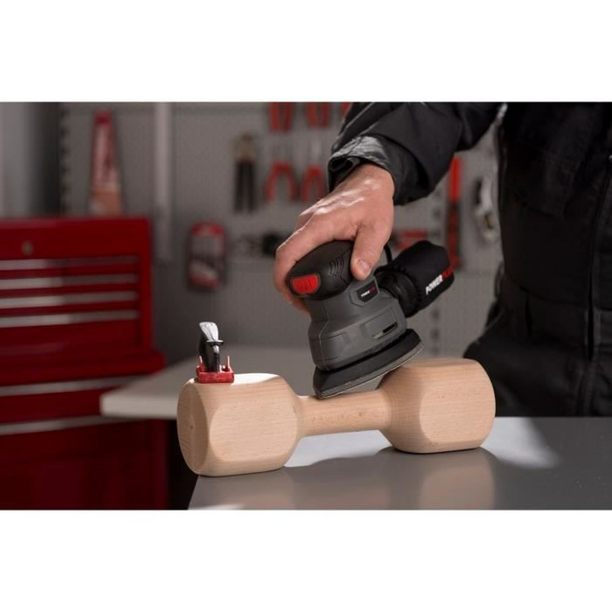 Eine Person schleift eine Holzhantel mit einem elektrischen Schleifwerkzeug.