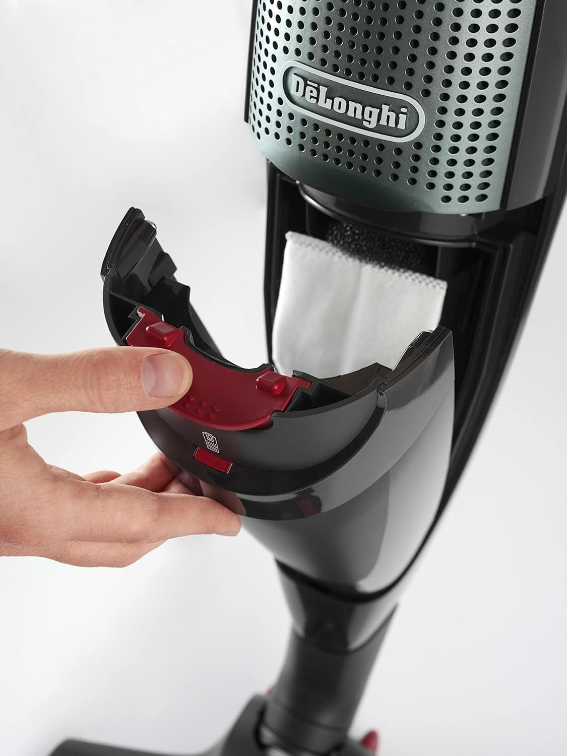 Dłoń otwiera komorę na kurz odkurzacza. Czerwona zatrzask i biały filtr widoczne.