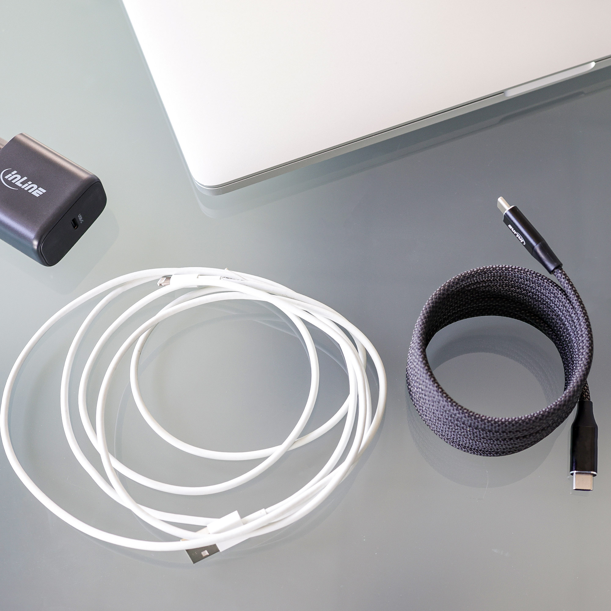 Câbles, chargeur et ordinateur portable sur une surface réfléchissante. Noir et blanc.
