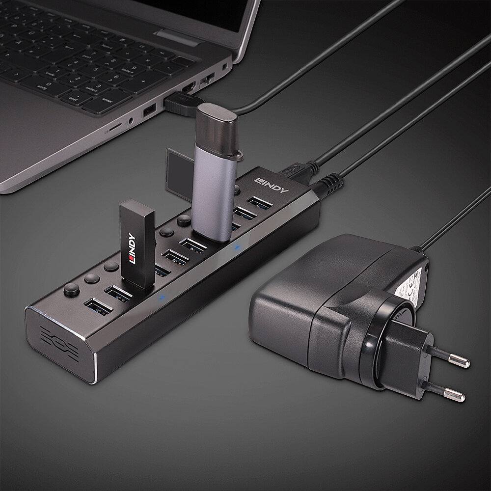 Hub USB nero con più porte USB, collegato a laptop e adattatore di alimentazione.