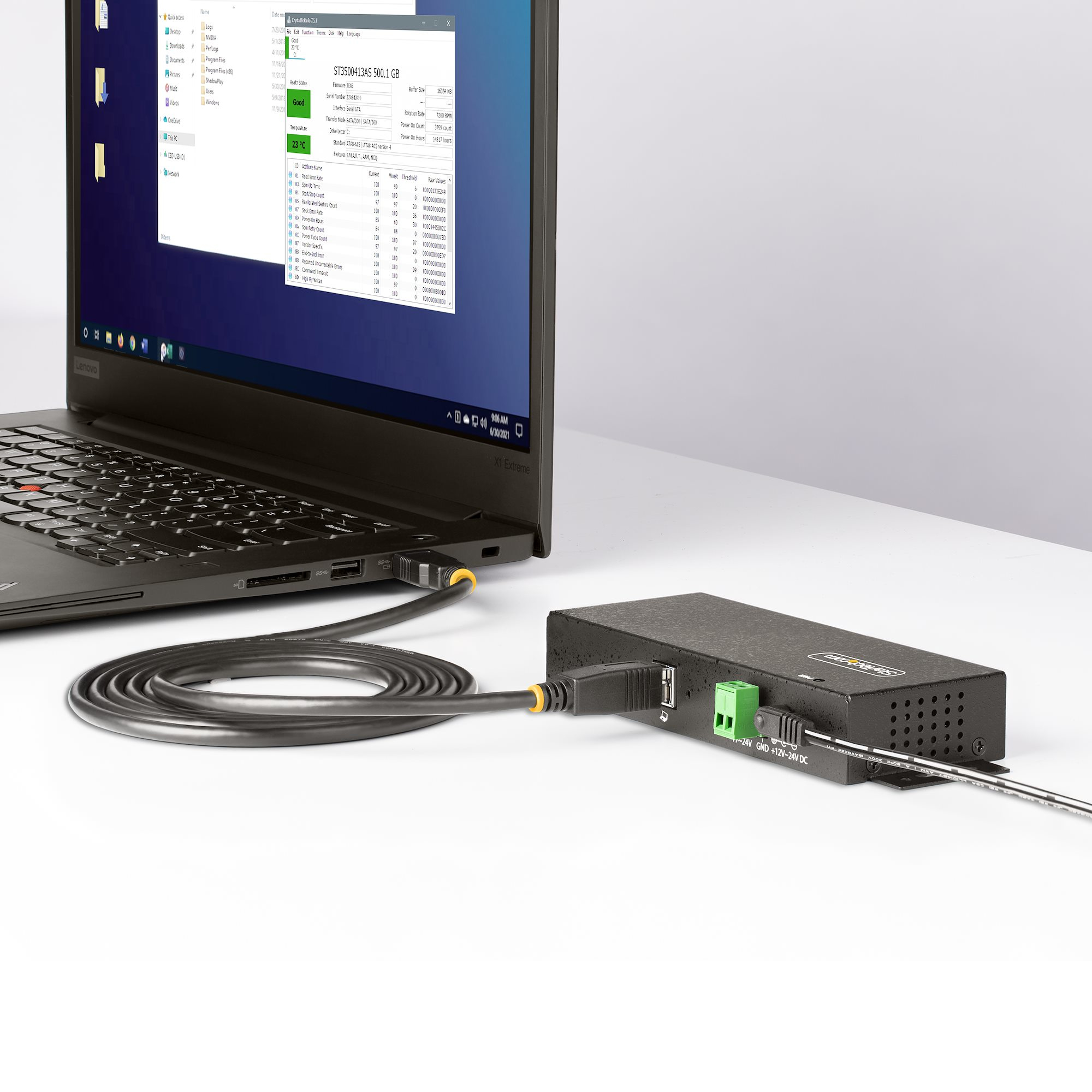 Laptop collegato a un hub nero. Lo schermo mostra file. Hub su una superficie bianca.