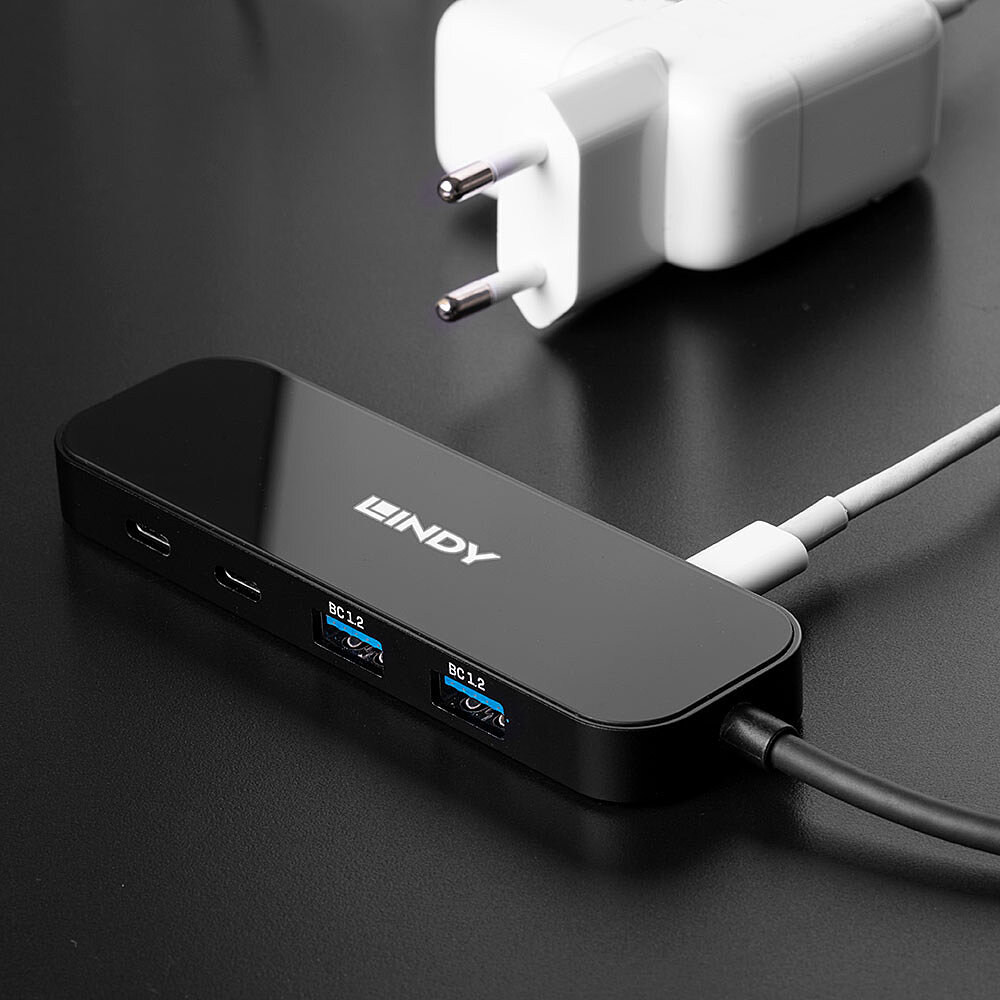 Hub USB nero con adattatore di alimentazione bianco. Porte USB. Lo sfondo è nero.