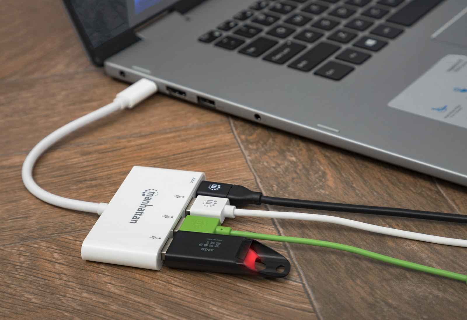 Un hub USB bianco collegato a un laptop con più cavi collegati. Sono visibili vari colori.