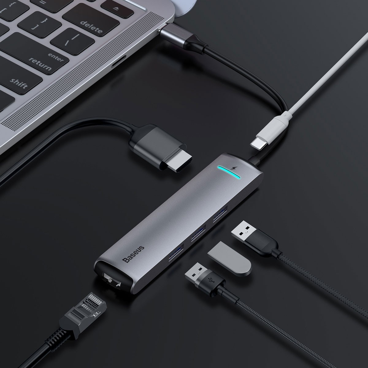 Hub USB Baseus grigio collegato a un laptop e a vari dispositivi esterni.