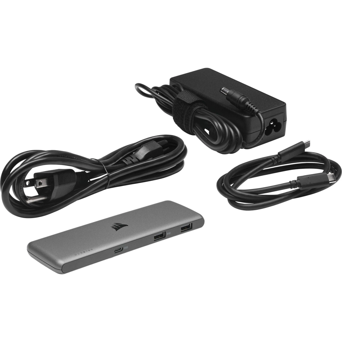 Adattatore nero, cavo di alimentazione, cavo USB-C e hub su superficie bianca.