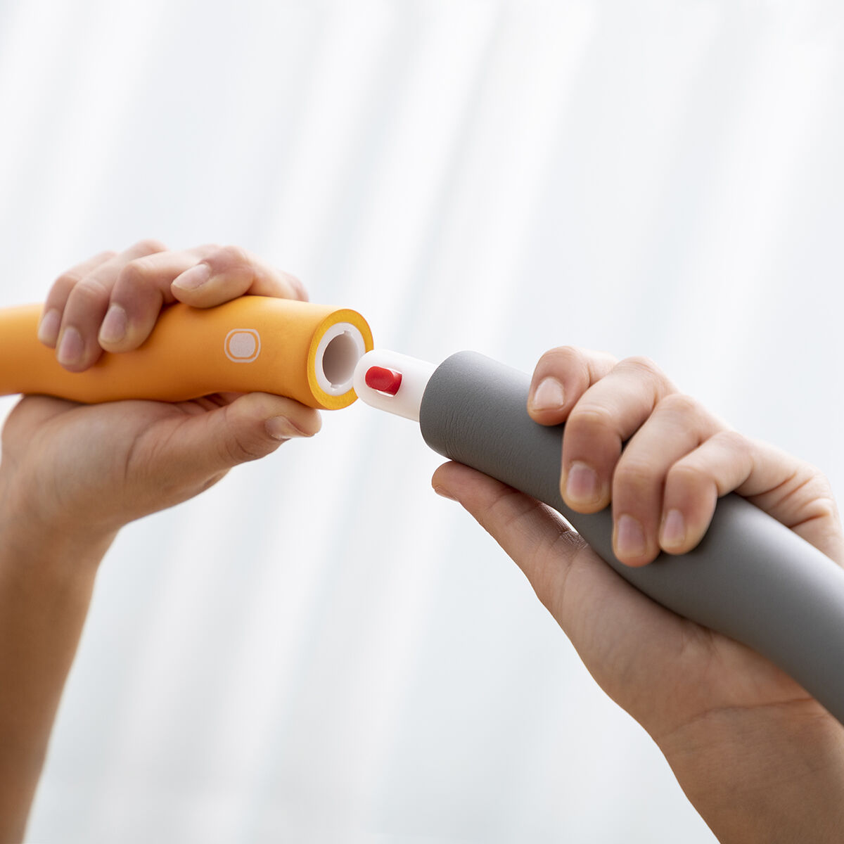 Due mani che collegano un tubo arancione e un tubo grigio su uno sfondo bianco.