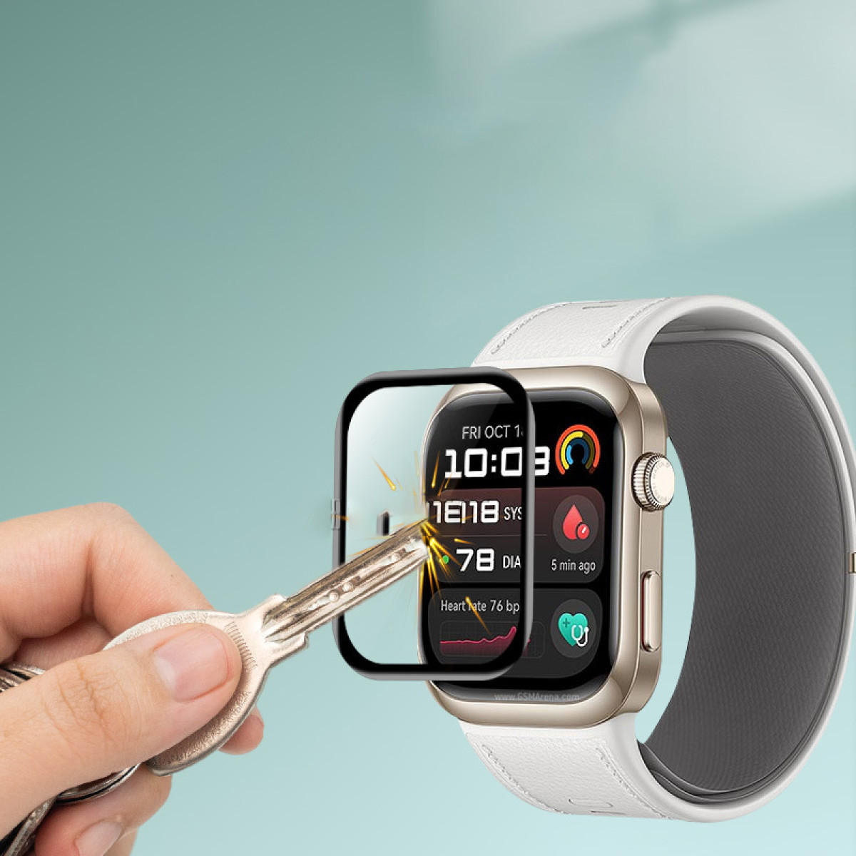 Eine Hand mit einem Schlüssel zeigt auf eine Displayschutzfolie auf einer Uhr. Uhr hat weißes Band.