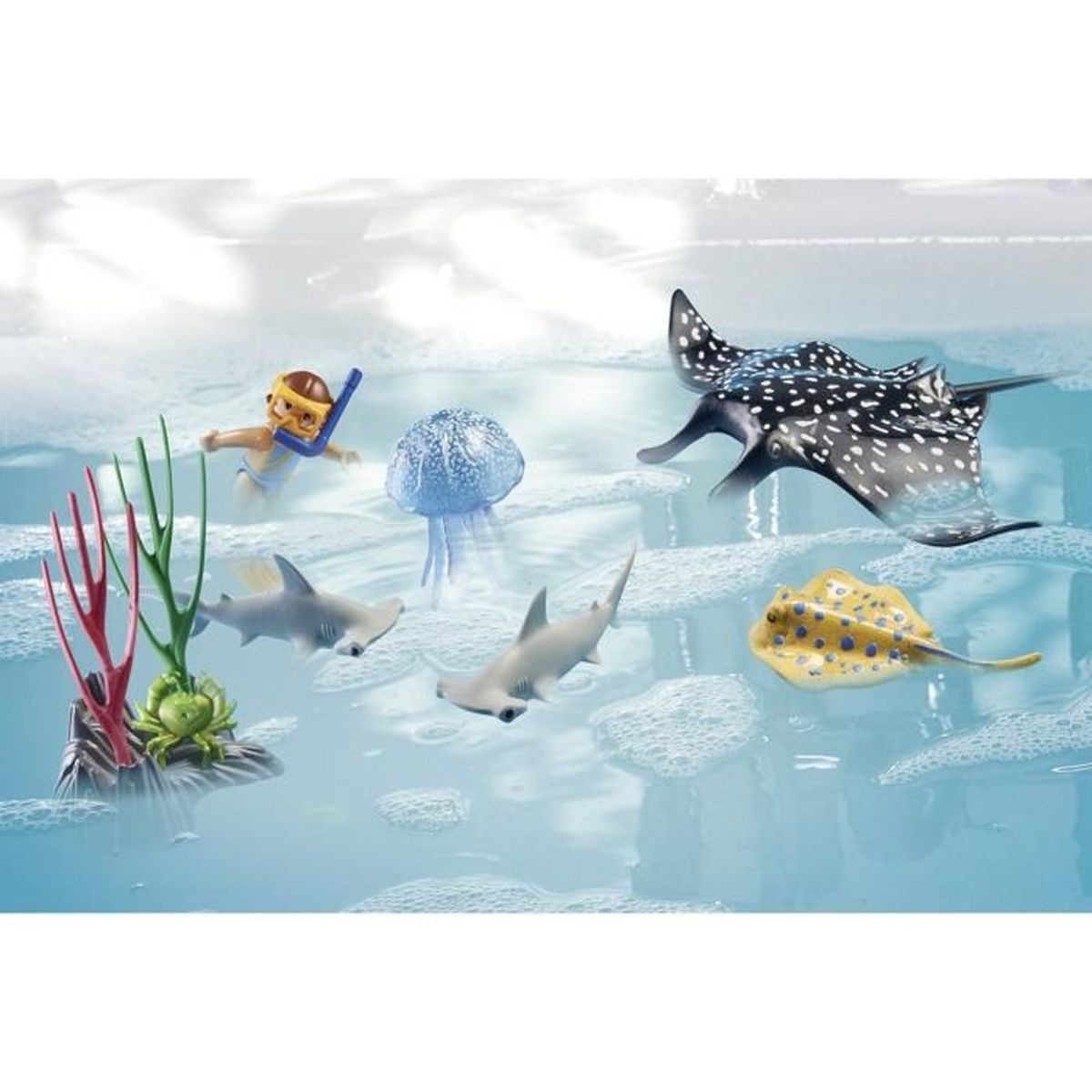 Scena giocattolo: subacqueo, medusa, squali, pastinaca e corallo, in acqua. Sfondo blu.
