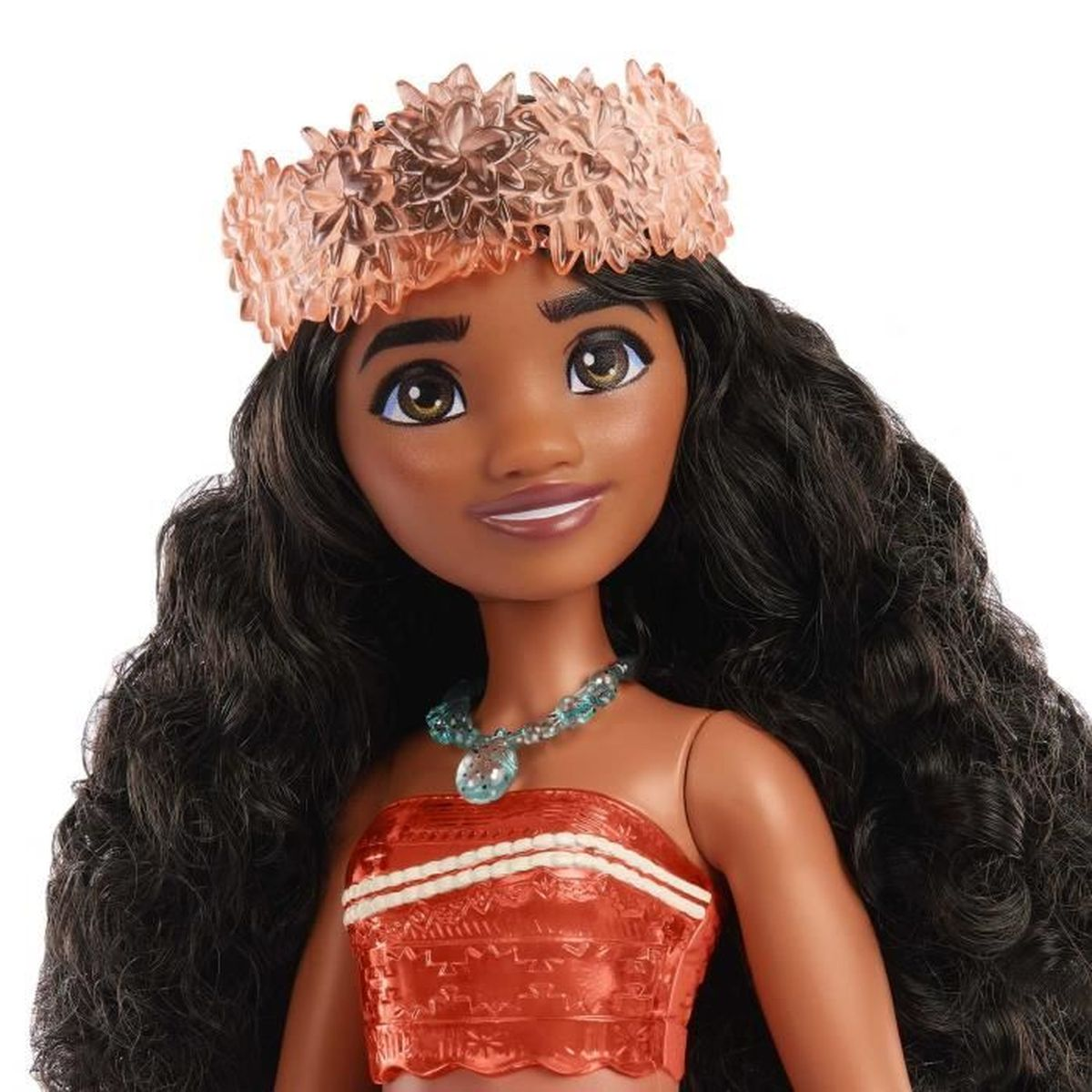 Una muñeca Moana con pelo largo negro, una corona de flores y un collar. Lleva una camiseta roja.