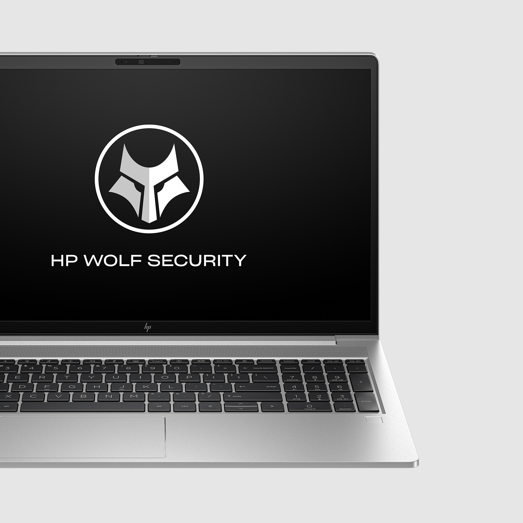 Ekran laptopa wyświetlający logo HP Wolf Security. Srebrny laptop, białe tło.