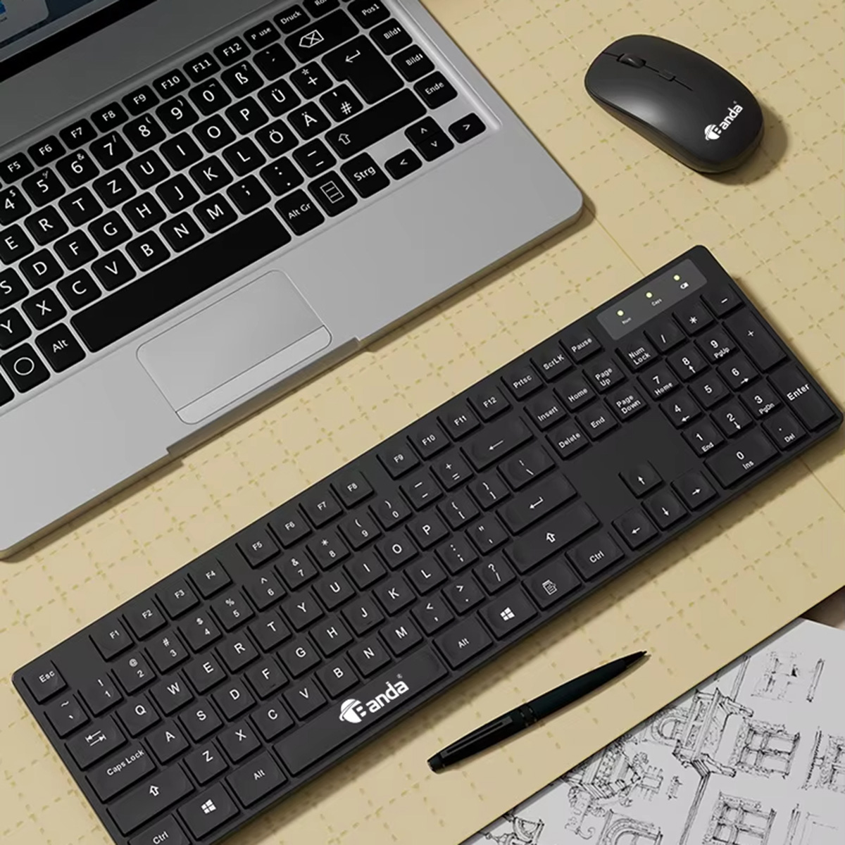 Portátil, teclado negro, ratón y bolígrafo sobre superficie con bocetos y notas.