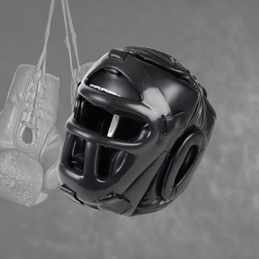 Casque de boxe noir, suspendu. Gants gris flous en arrière-plan.