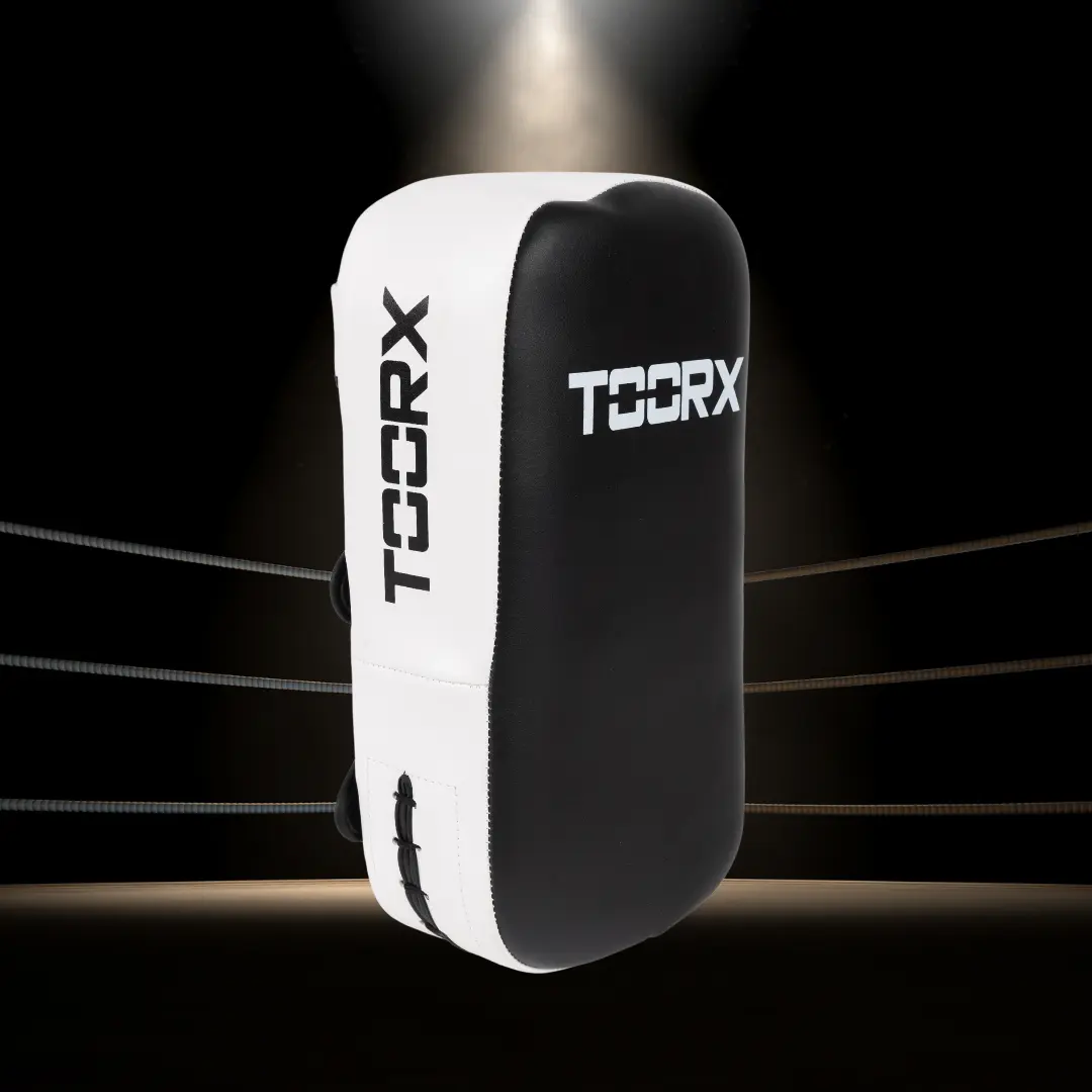 Boks pad, wit en zwart met 'TOCRX' tekst. Achtergrond toont een boksring.