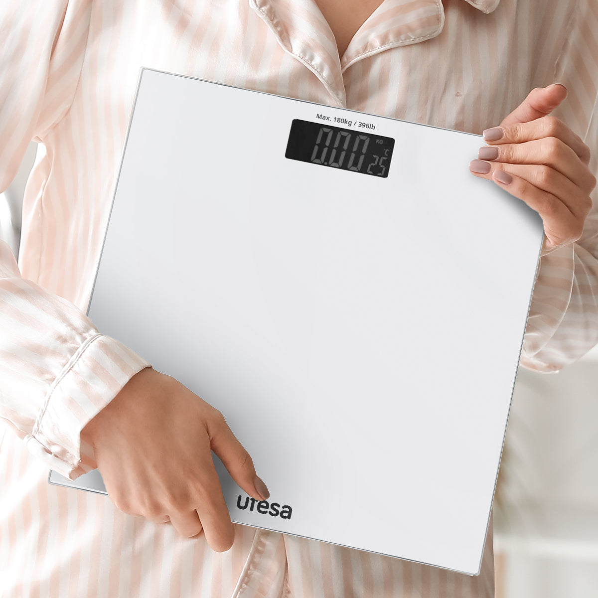 Una mujer sostiene una báscula digital blanca. La báscula muestra 000,25 kg. La marca Utresa es visible.