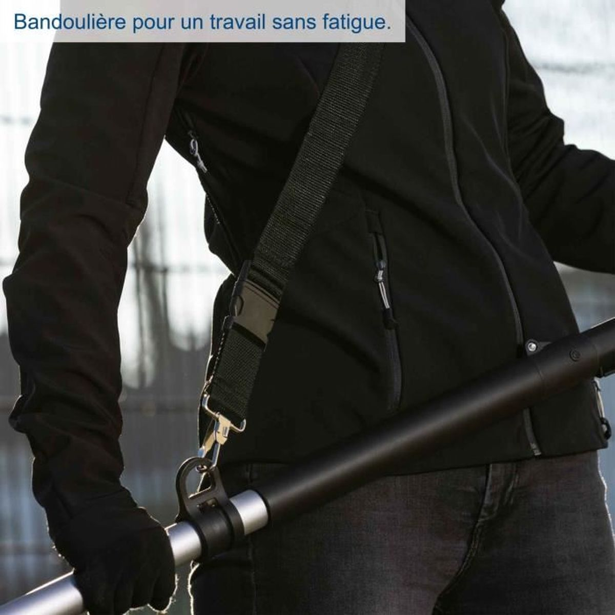 Person in schwarzer Kleidung mit einem schwarzen Riemen, der an einem Werkzeug befestigt ist.