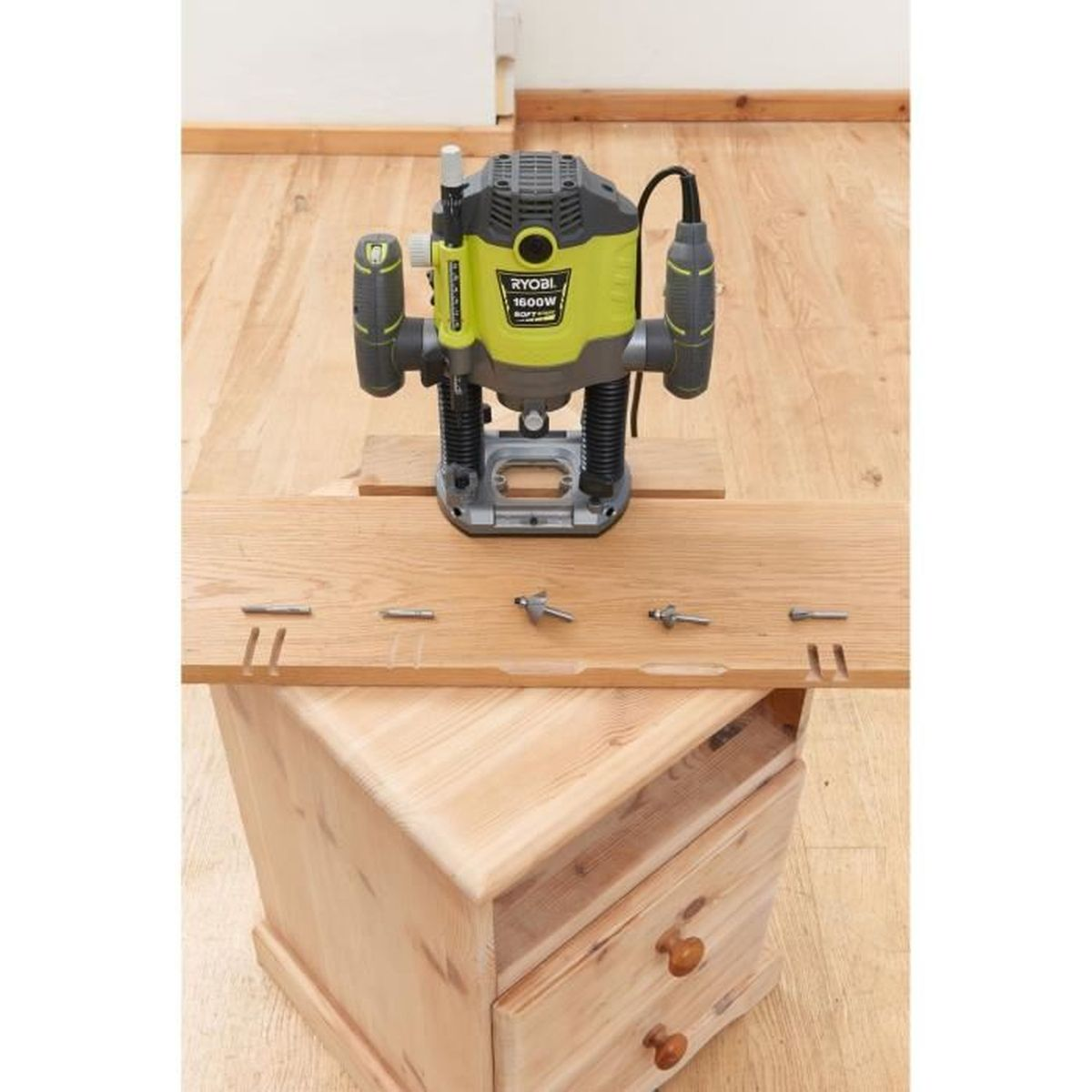 Ein Router mit Holzstück und Werkzeugen, auf einer Holzschublade platziert.