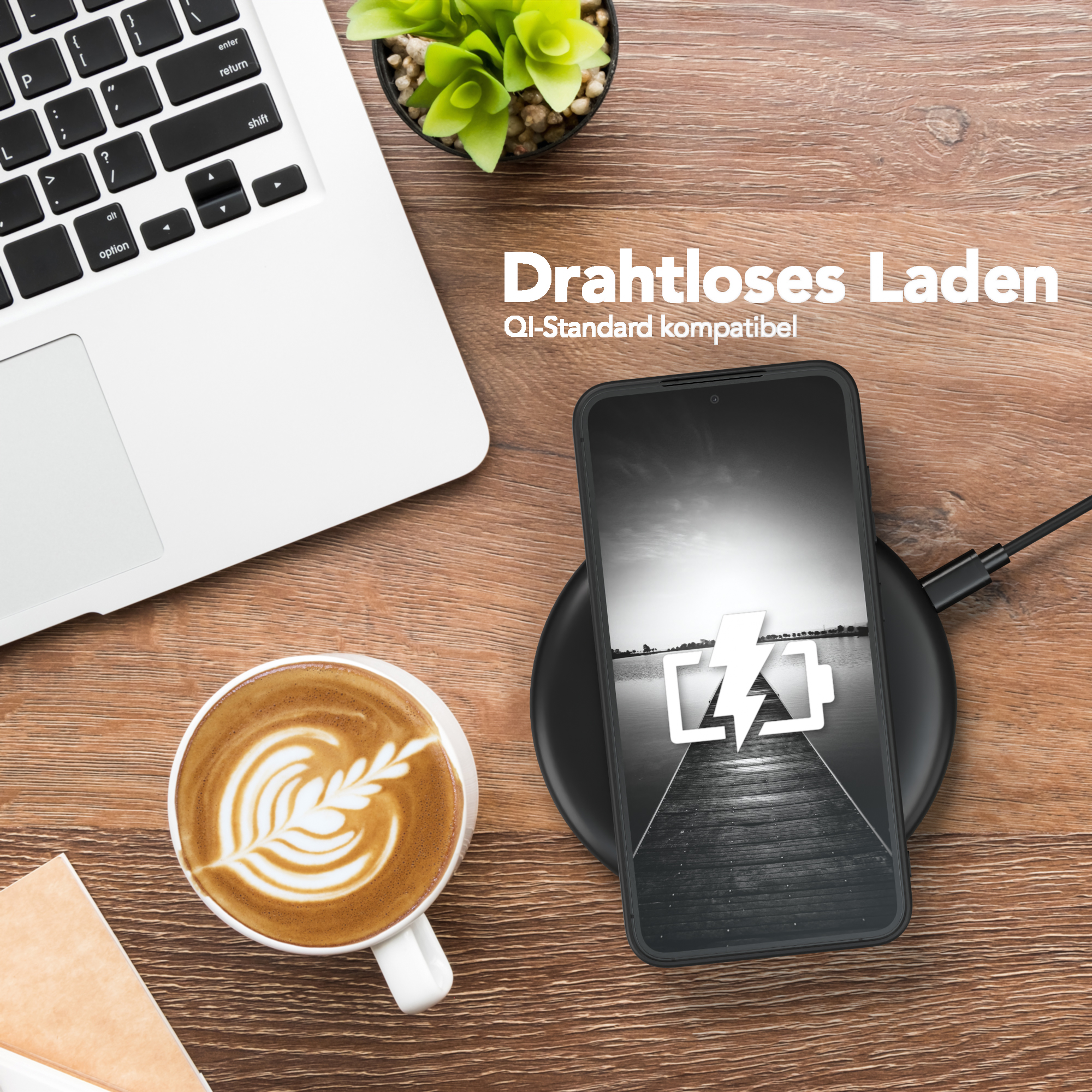 Telefon auf kabellosem Ladegerät. Laptop, Kaffeetasse und Pflanze auf Tisch.