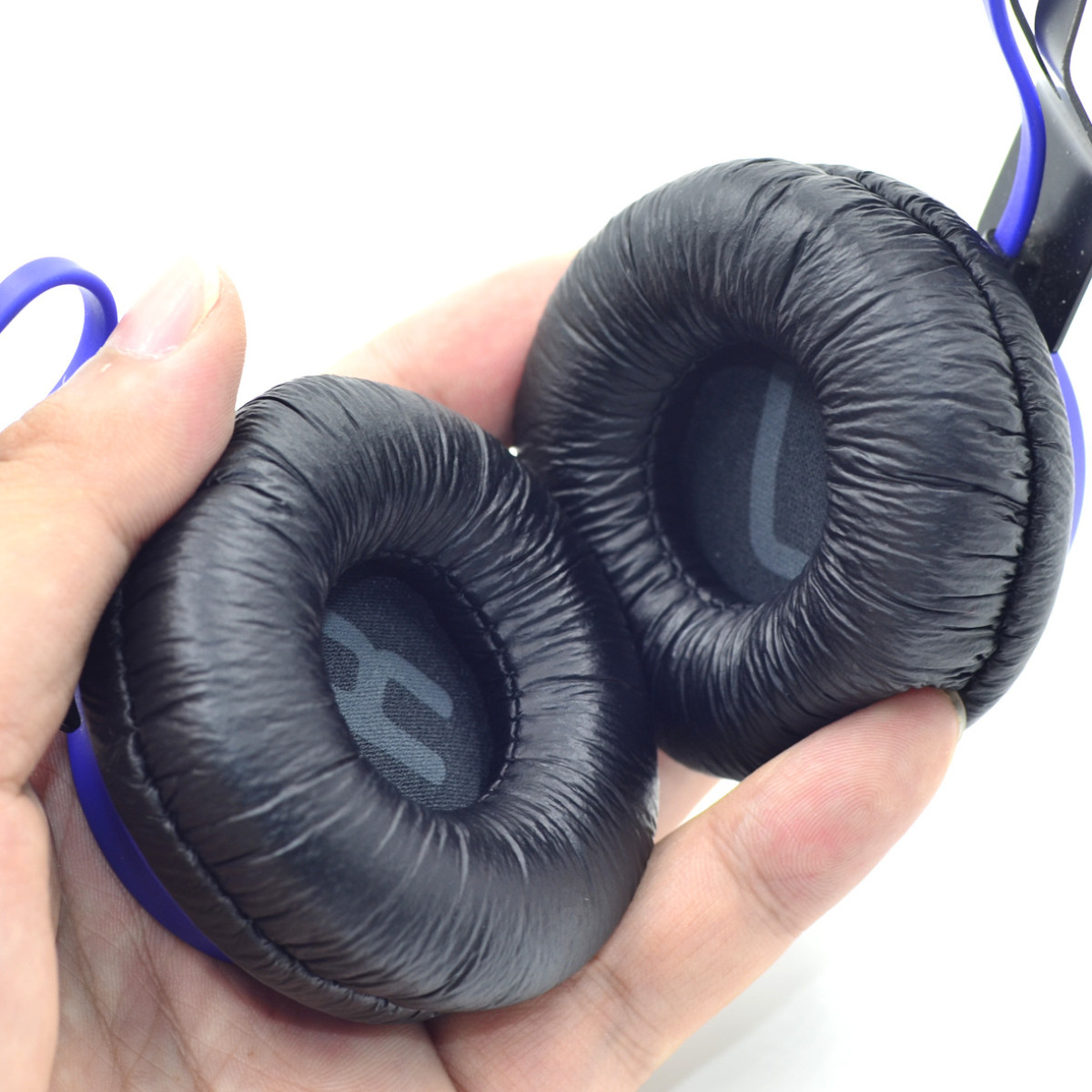 Schwarz-blaue Kopfhörer, gehalten von einer Hand. Ohrmuscheln sind sichtbar, mit 'R' und 'L'.