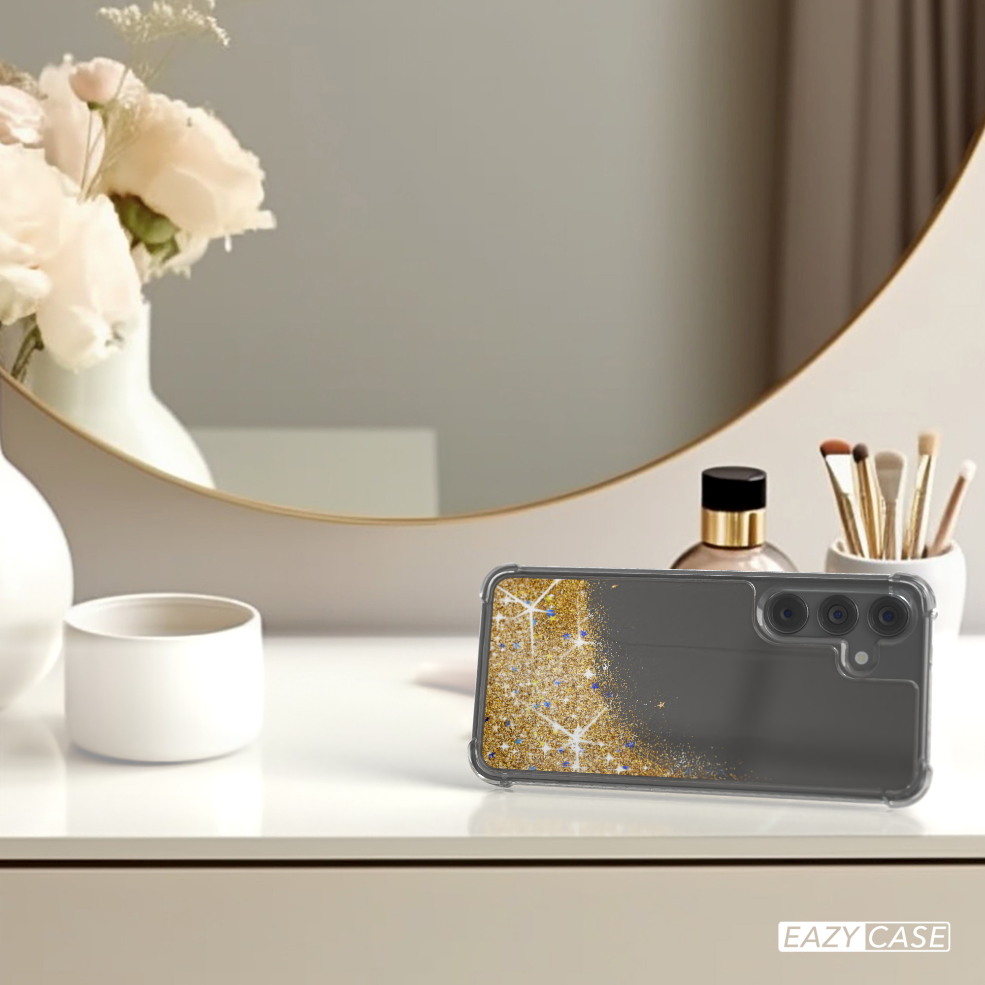 Handyhülle auf einem Tisch mit Spiegel und Blumen, zeigt Goldglitzer-Design.