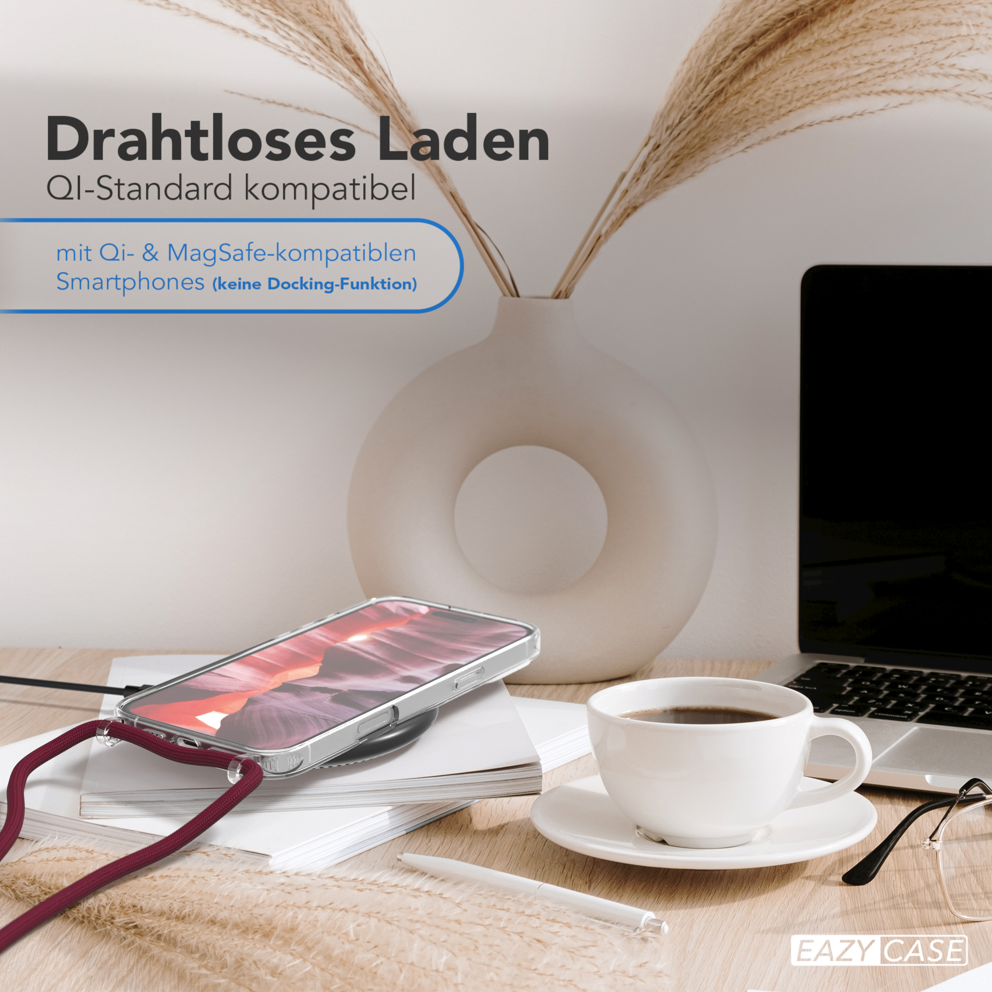 Ein Smartphone auf einem Ladepad neben einer Kaffeetasse und einem Laptop auf einem Holztisch.