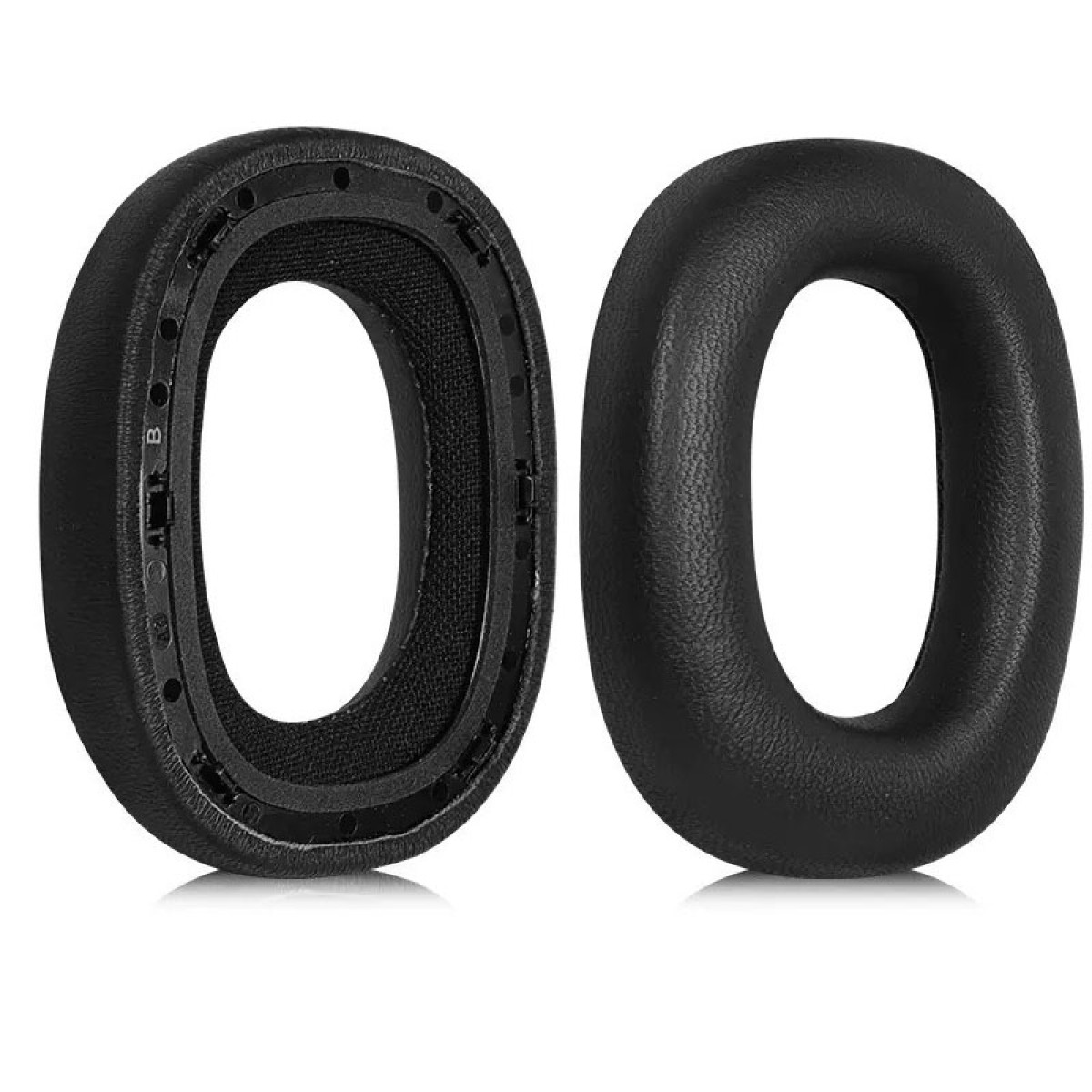 Dwie czarne poduszki na uszy, jedna pokazuje wewnętrzną siatkę i szczegóły montażu. Białe tło.