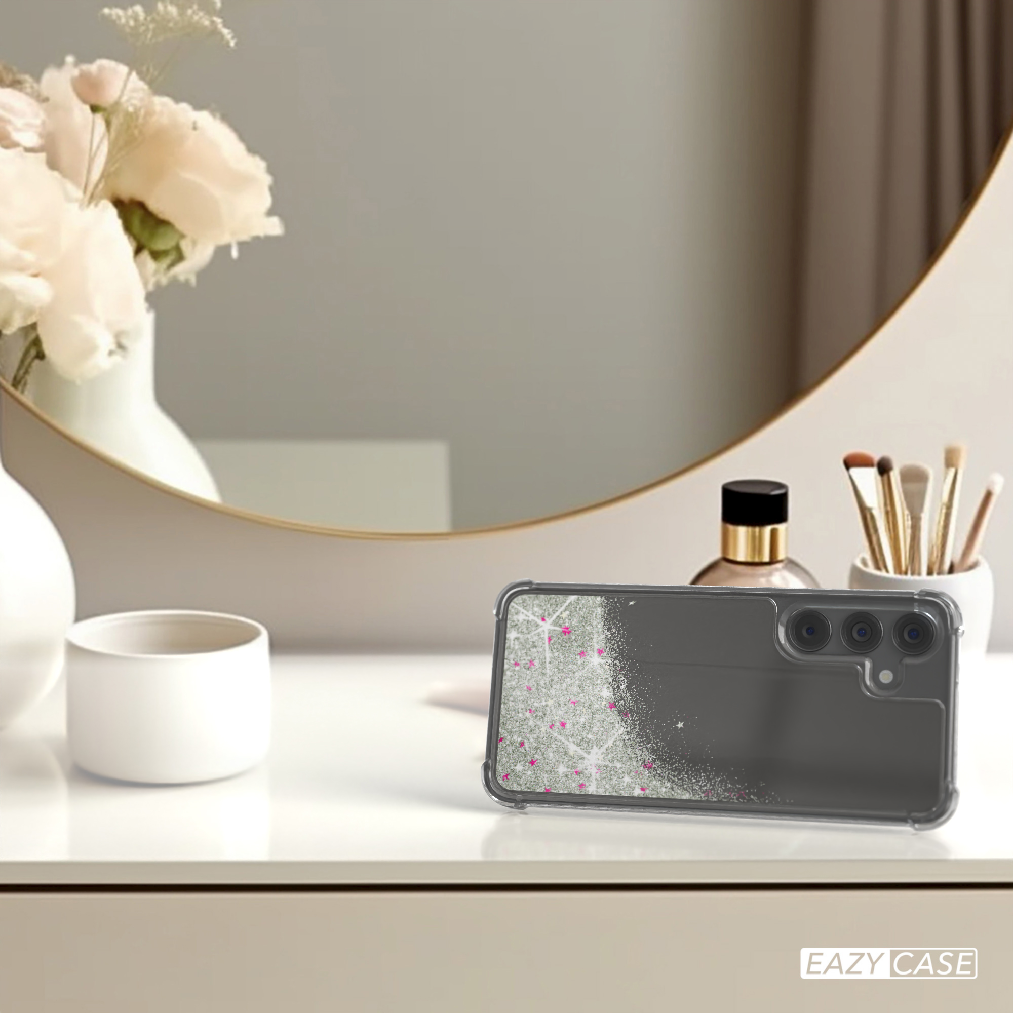 Eine Handyhülle mit Glitzer und einem Telefon darin, auf einem Tisch mit Spiegel und Deko.