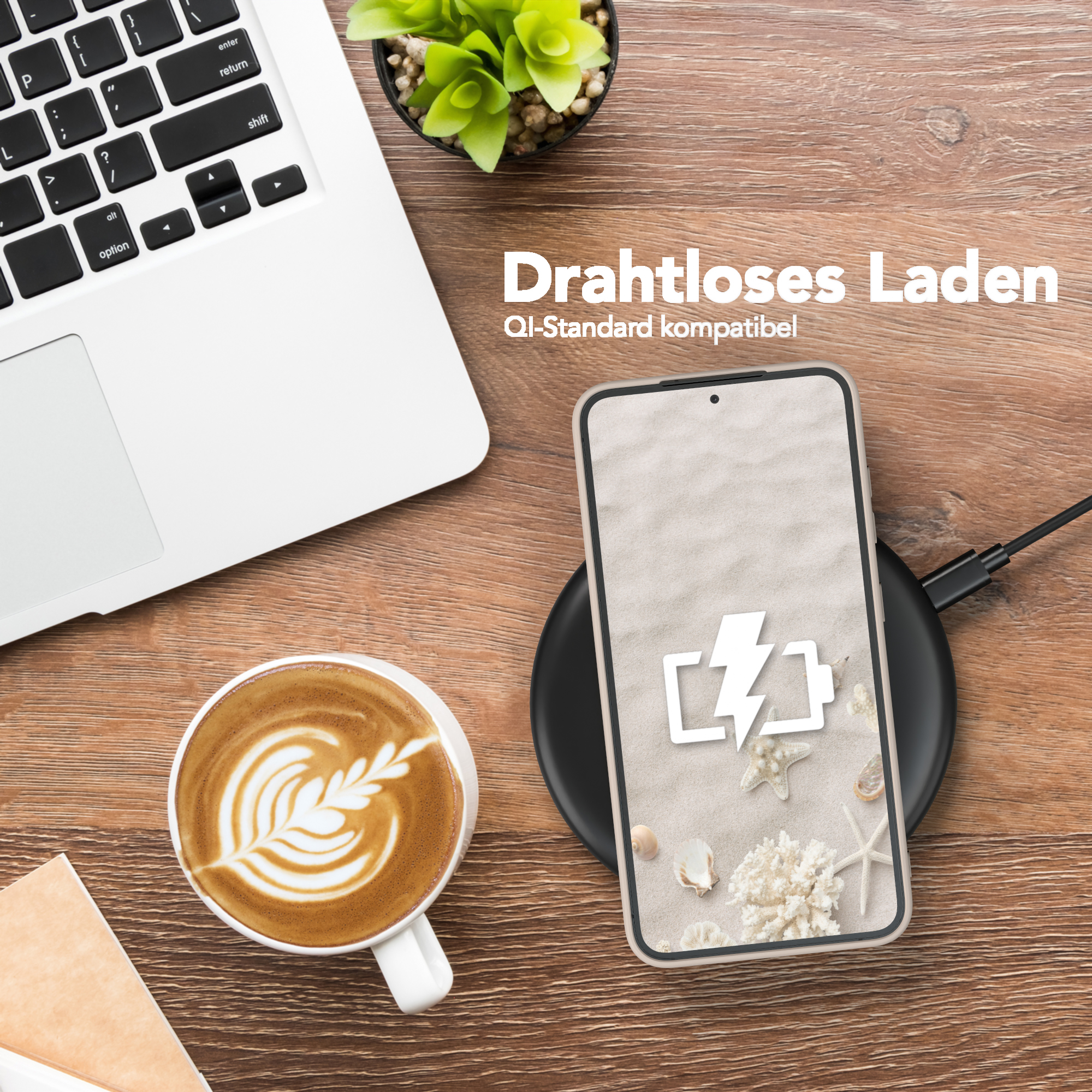 Telefon auf Ladegerät, Laptop, Kaffee und Pflanze auf Holzschreibtisch.