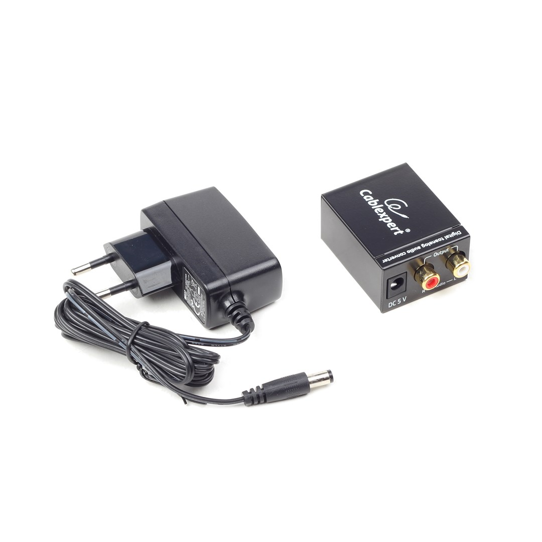 Adaptador de corriente negro y convertidor de audio digital con cables, sobre fondo blanco.