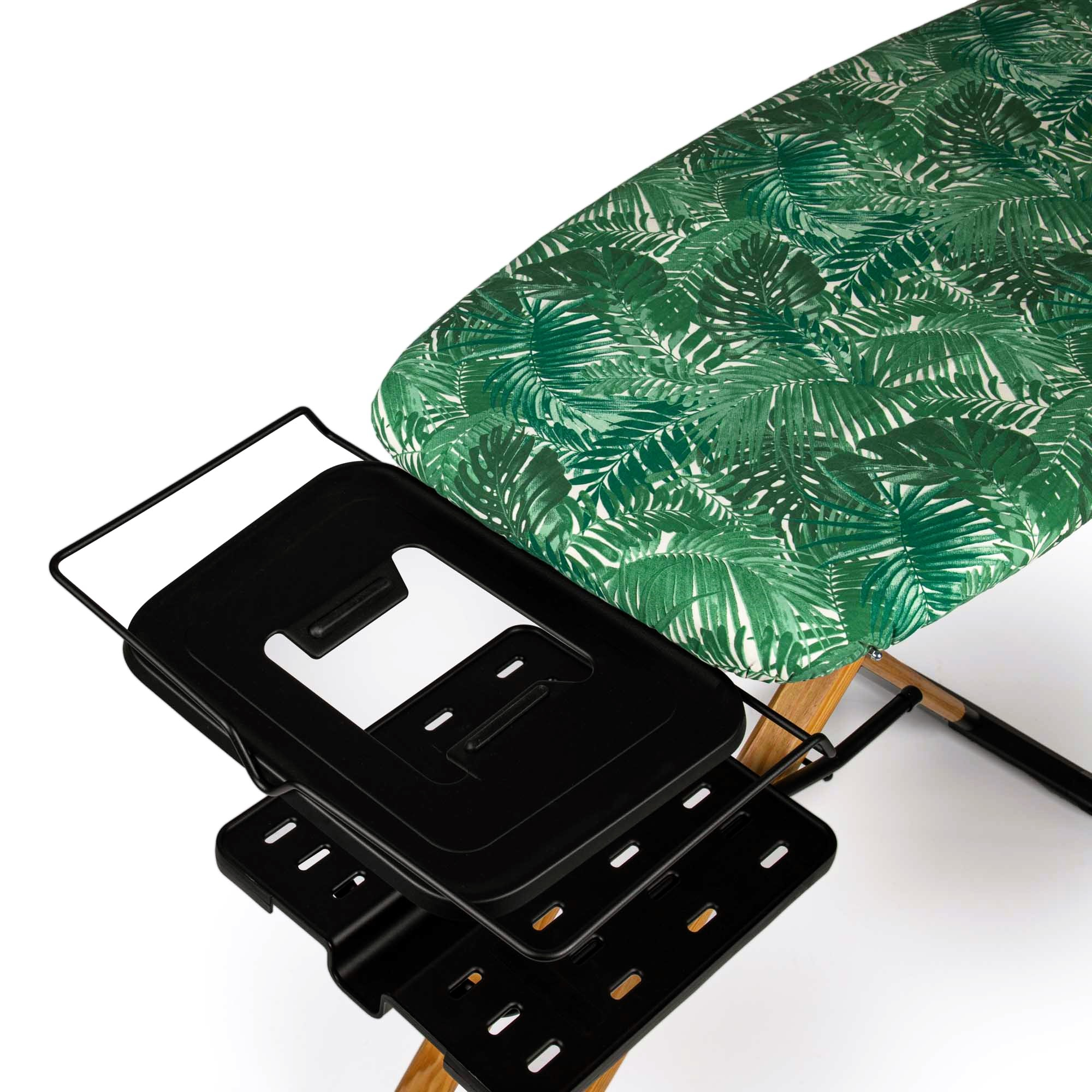 Tabla de planchar con estampado de hojas verdes, soporte negro y patas de madera.