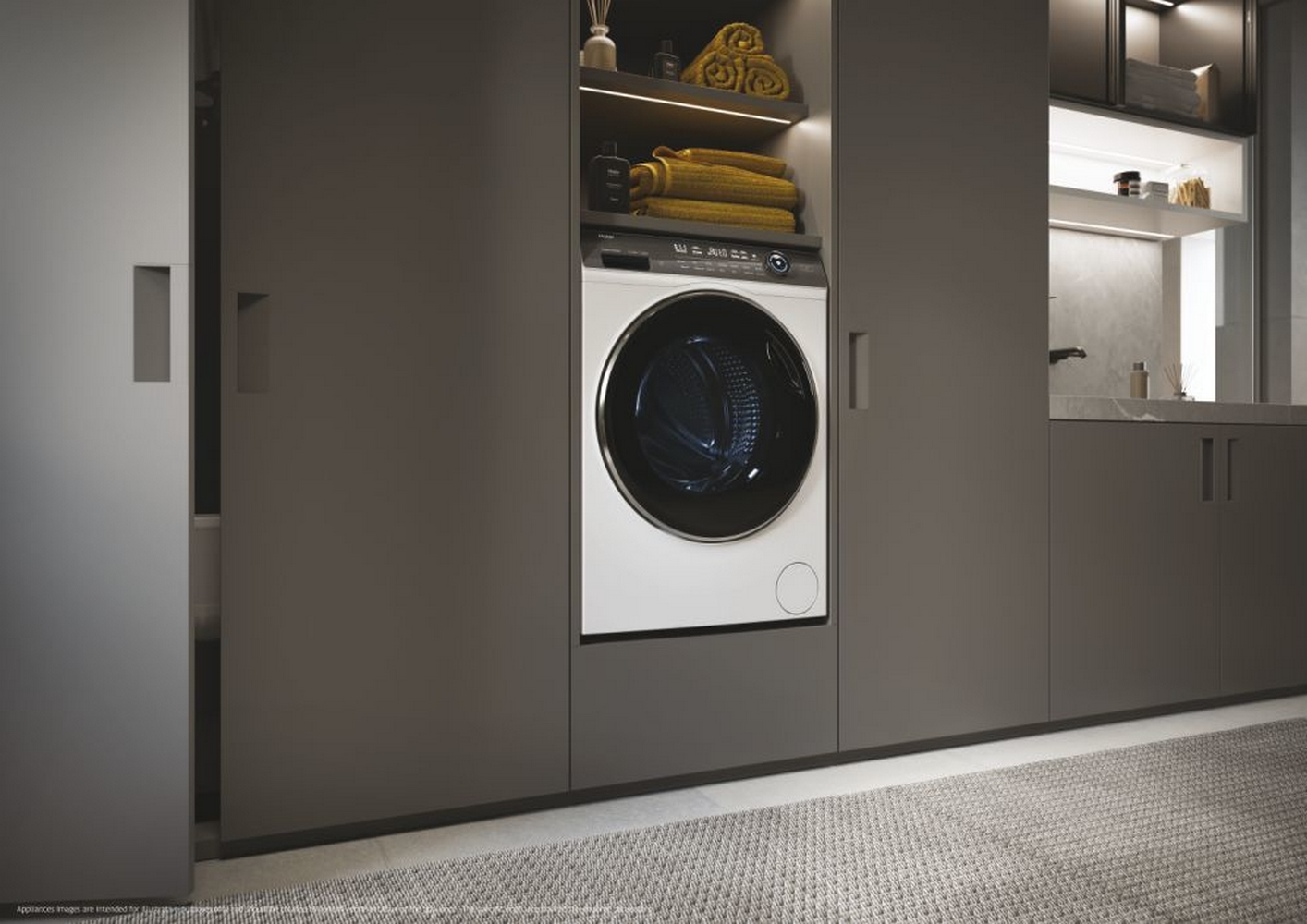 Una lavatrice bianca installata all'interno di un mobile scuro in un bagno.