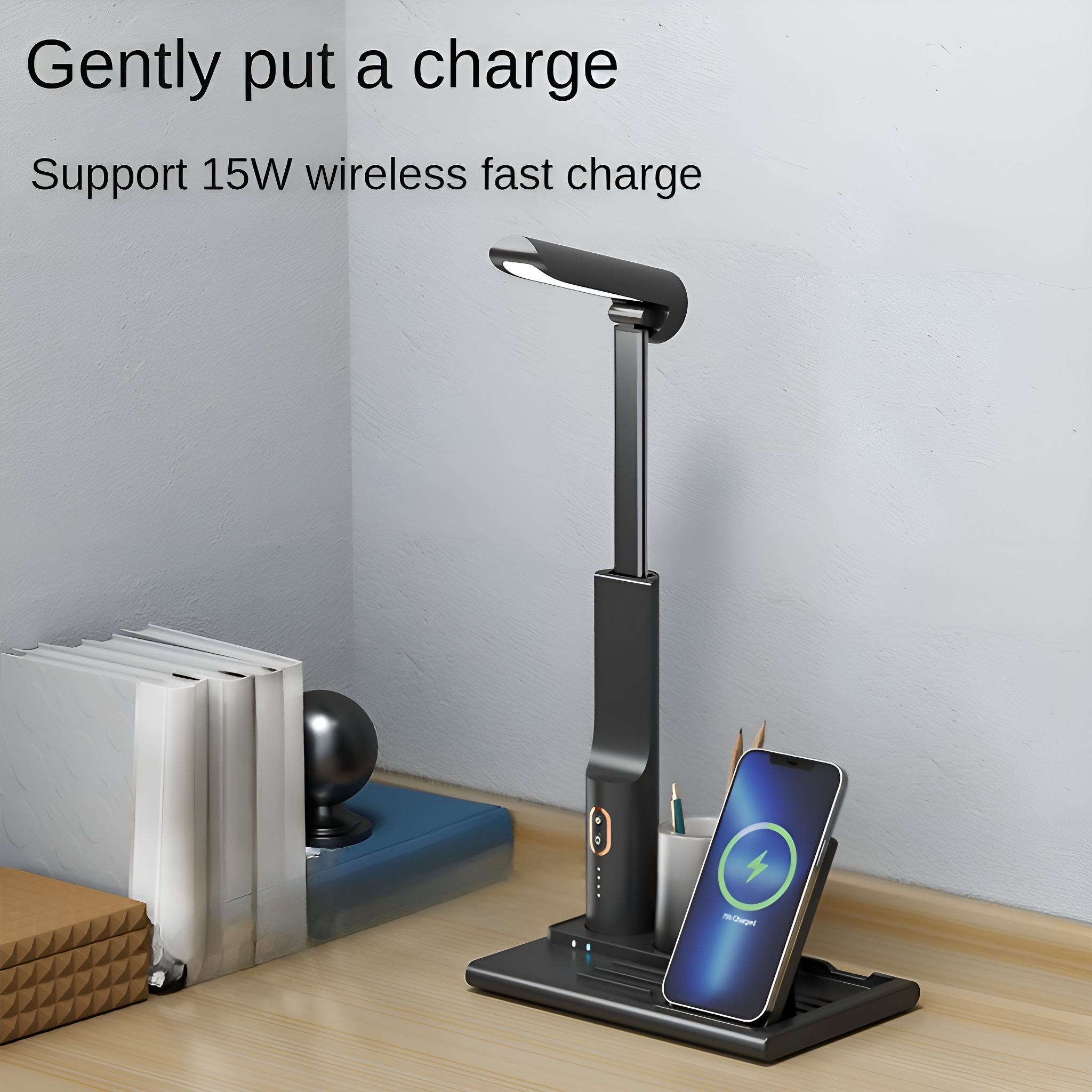 Schwarze Schreibtischlampe mit Ladestation für Telefon. Bücher und Pflanze daneben.